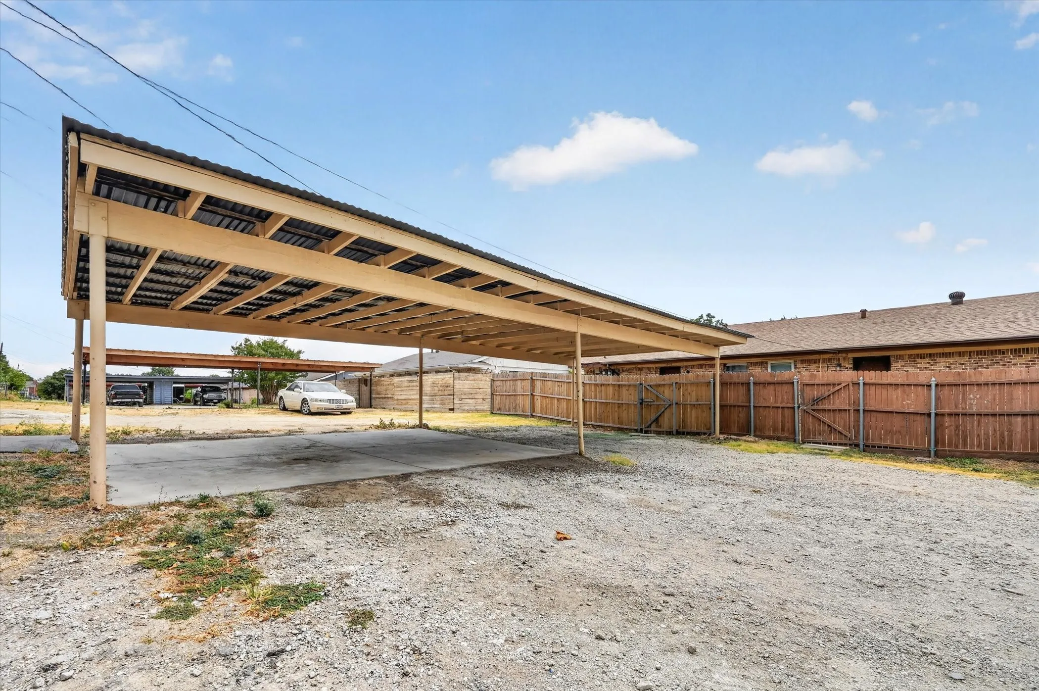 Spacious covered carport with steel beam construction and solar panel array overhead, providing ample parking and shade