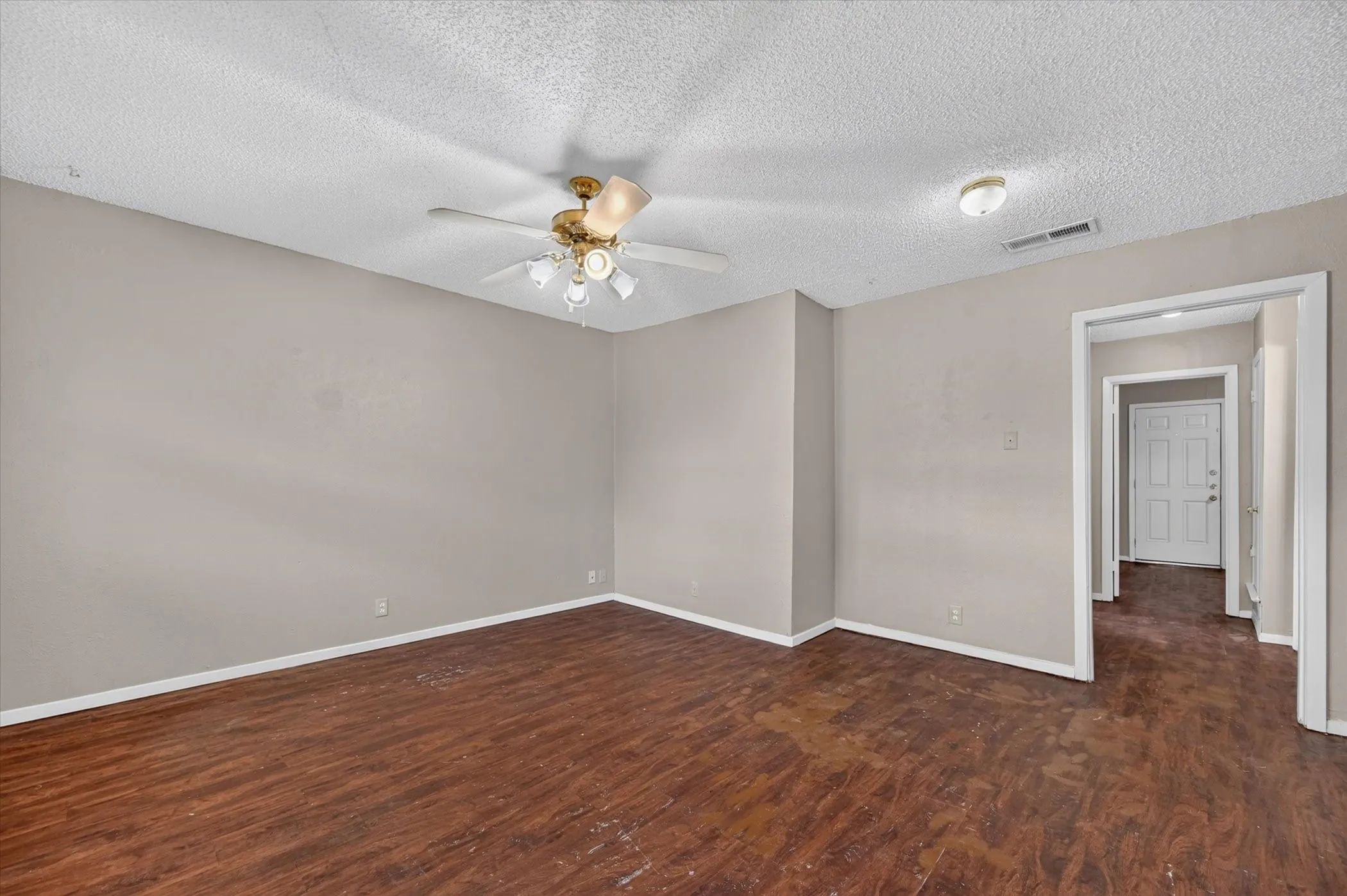 Wood-finish flooring with neutral wall tones and a ceiling fan with integrated lighting