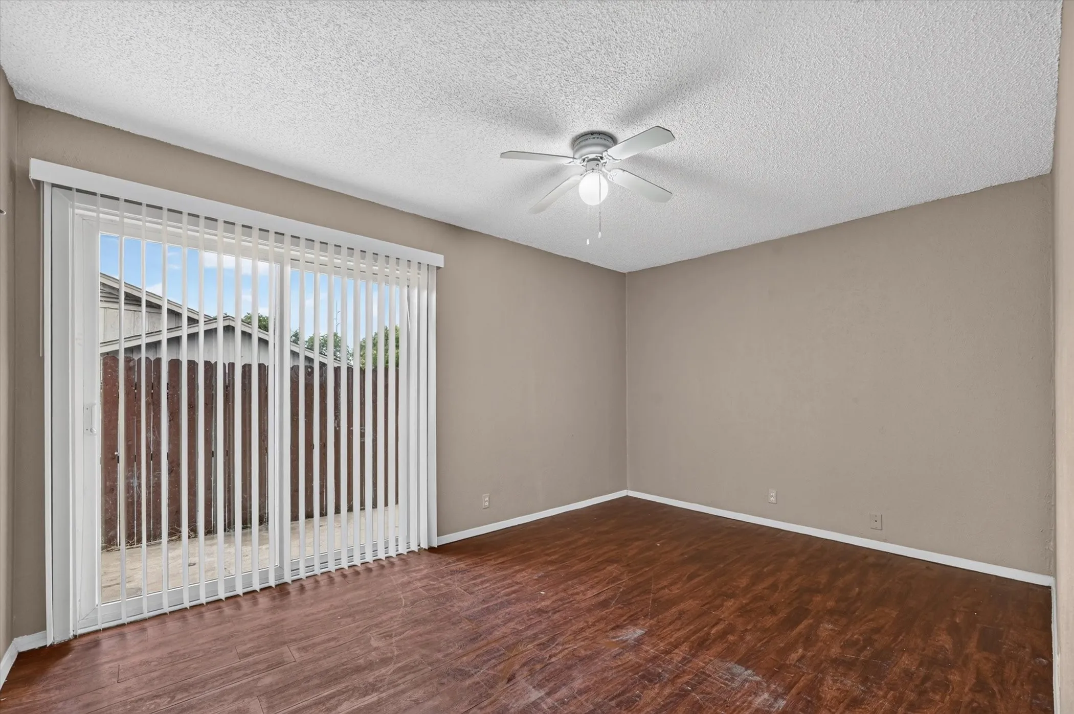Wood-finish flooring, neutral wall paint, and a ceiling fan with integrated lighting