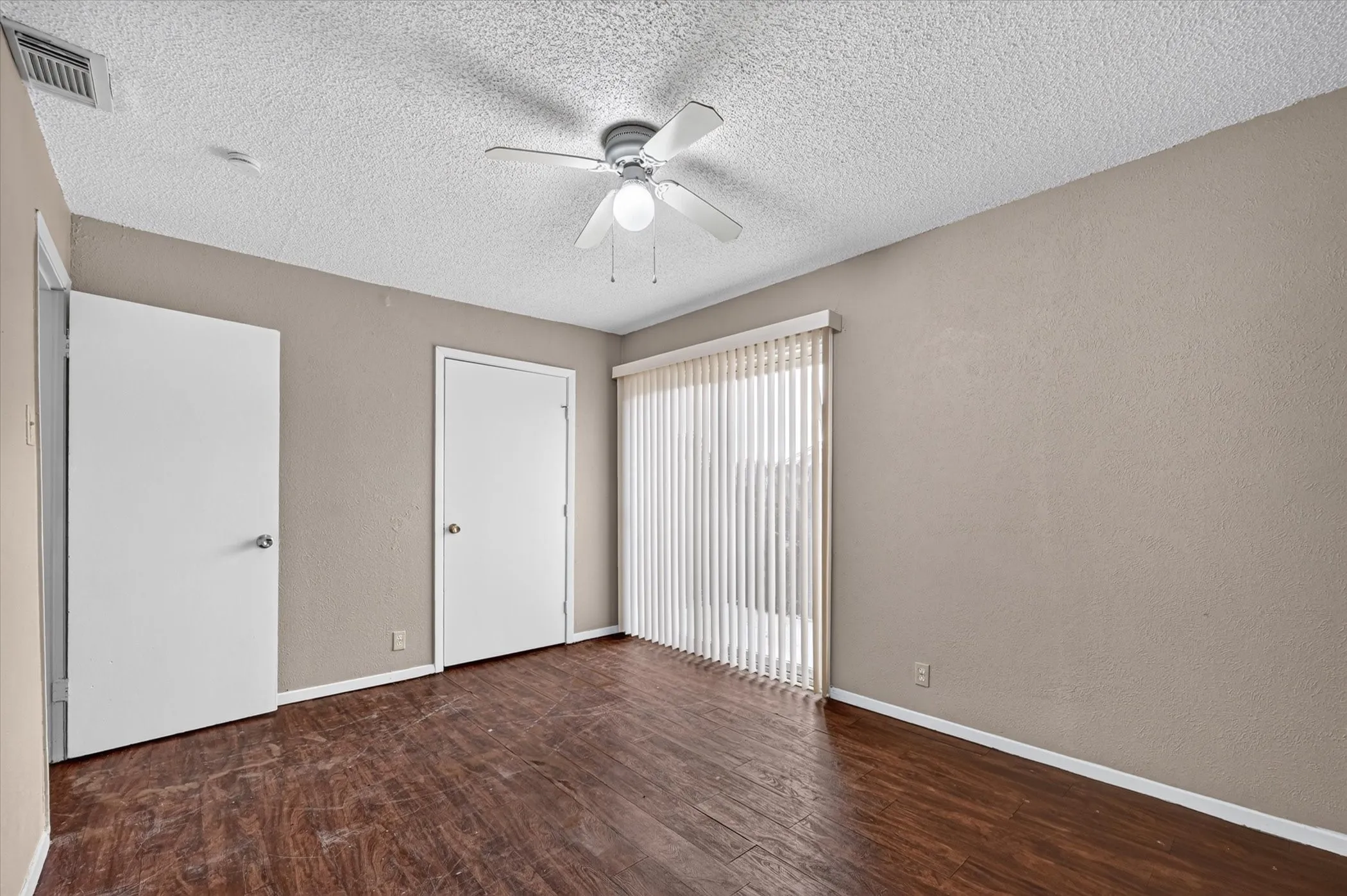 Wood-finish flooring, vertical blinds, and a ceiling fan with integrated lighting