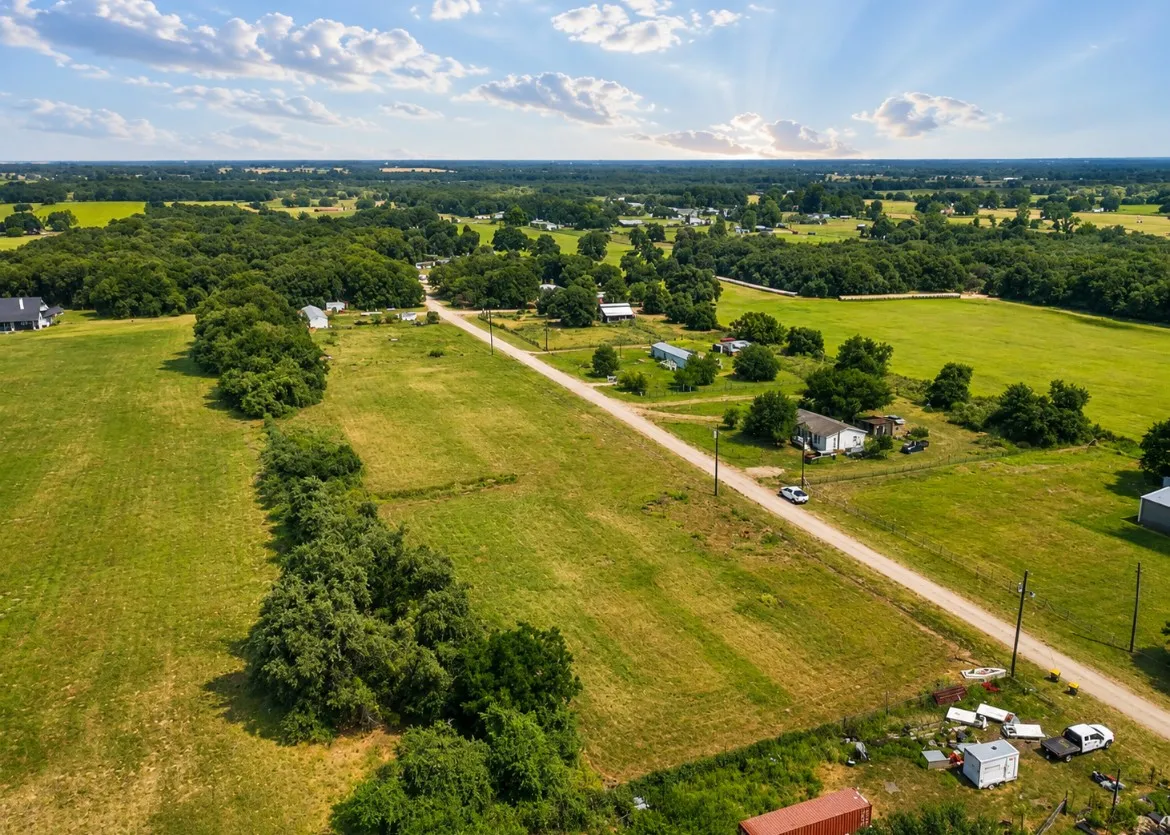 Expansive green acreage with a tree-lined perimeter, bordered by a rural road