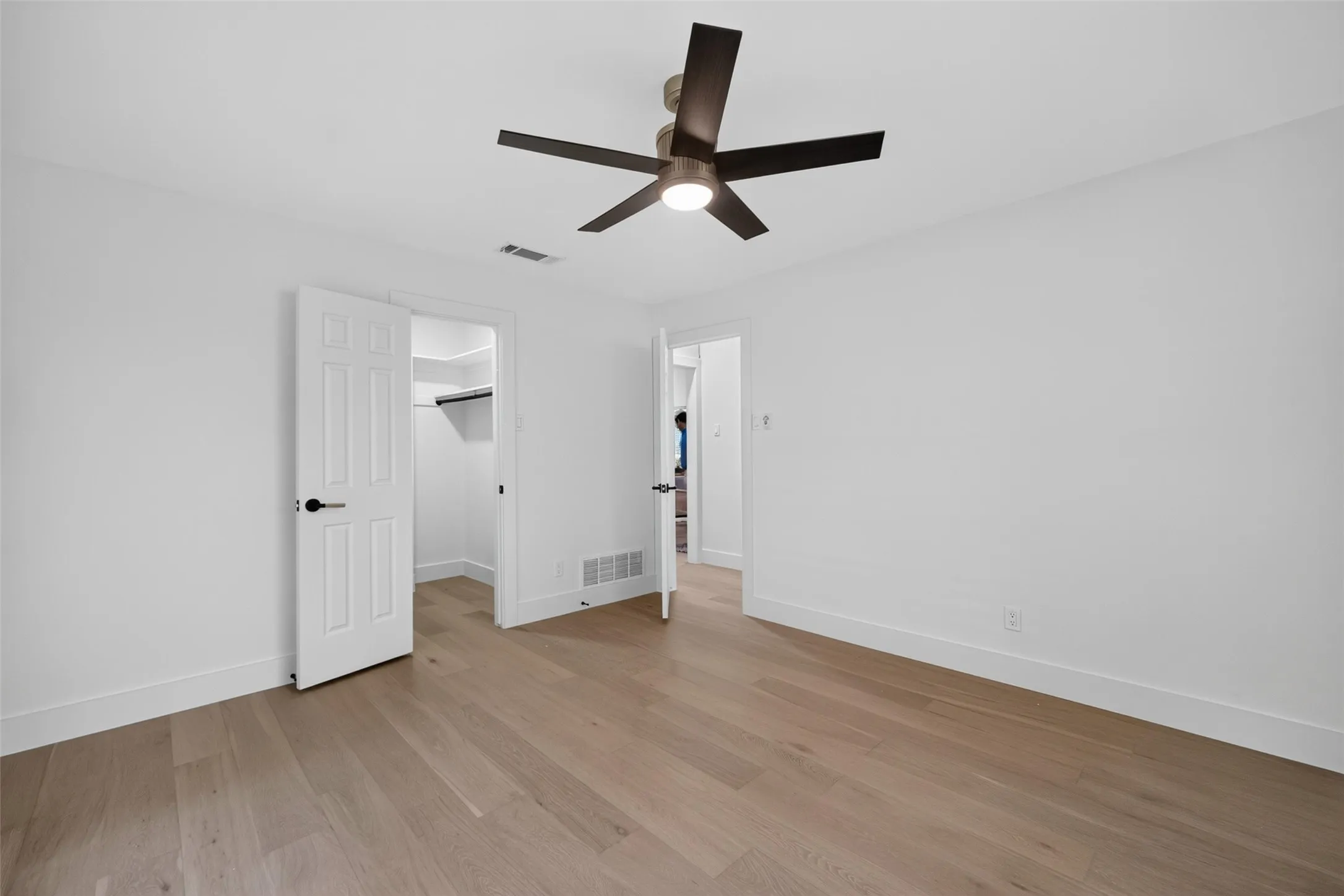 Wood-finish flooring, white walls, and a contemporary ceiling fan with integrated lighting