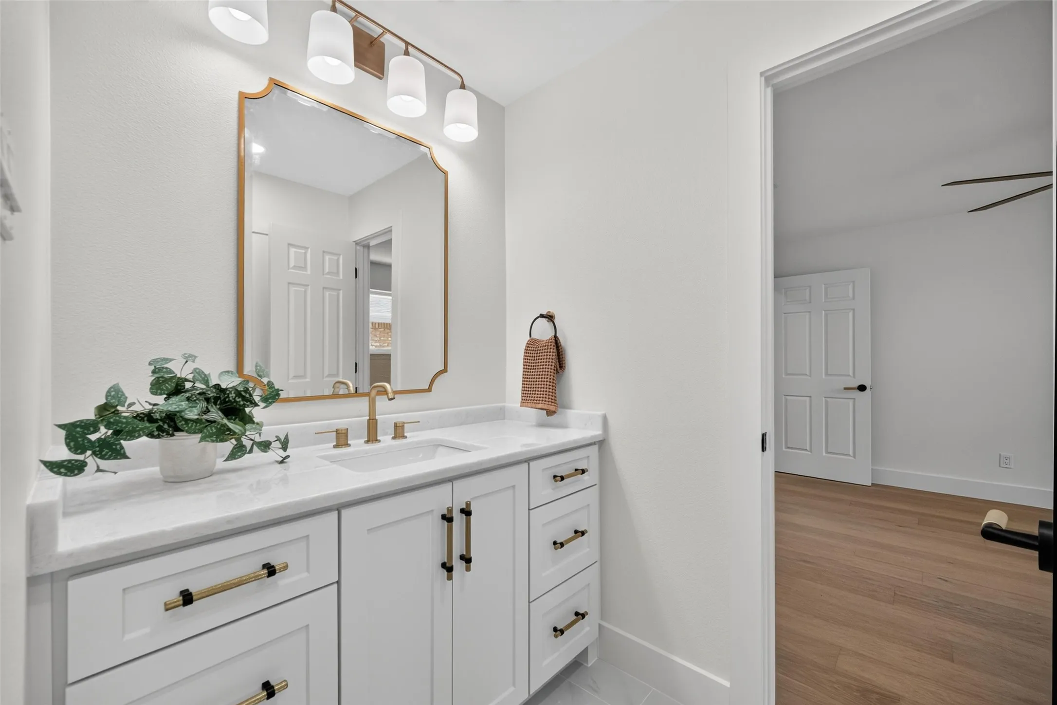 White vanity with a rectangular undermount sink, brass-finish faucet, and coordinating hardware