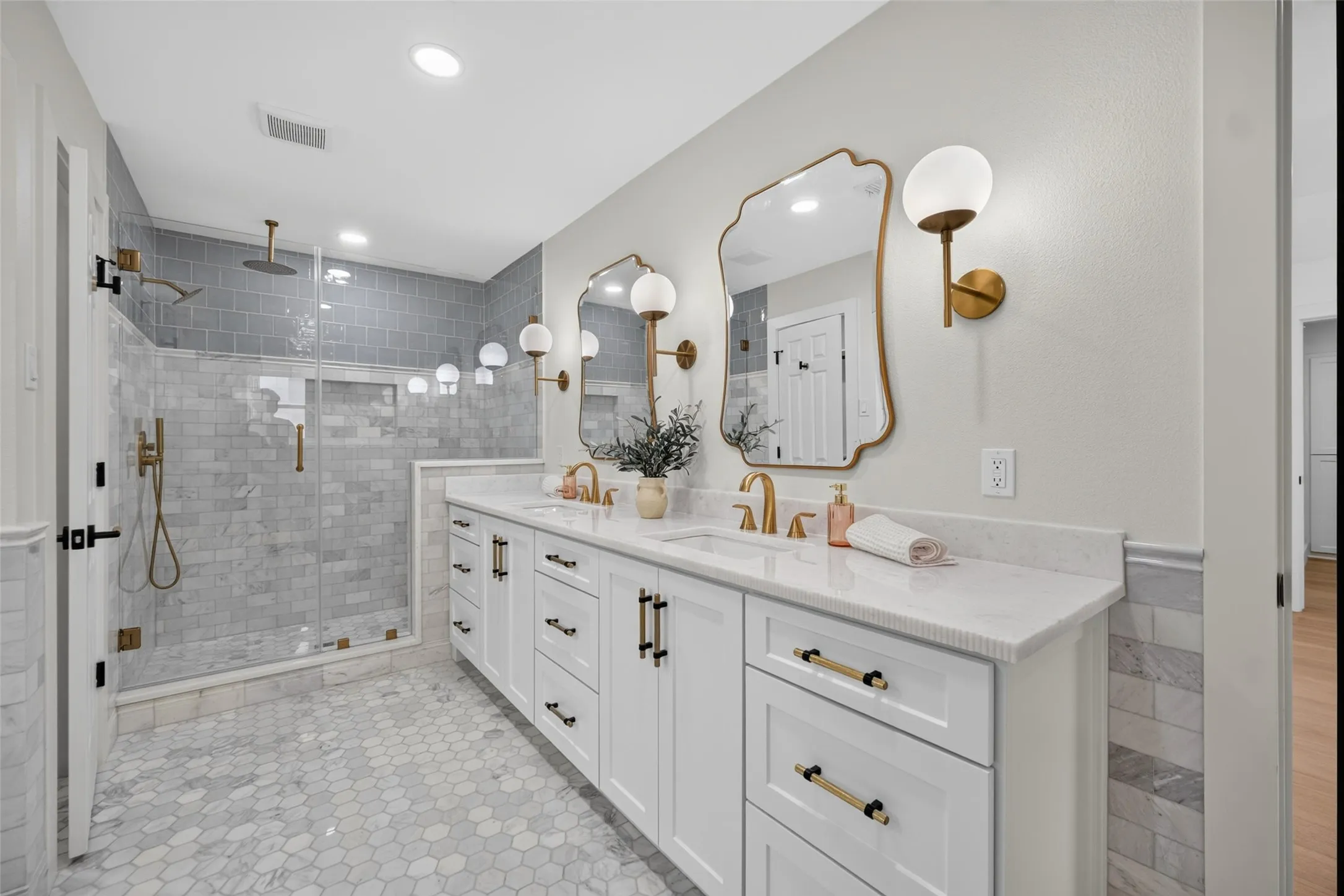 Dual vanity with undermount sinks, stone countertops, and gold-finish fixtures