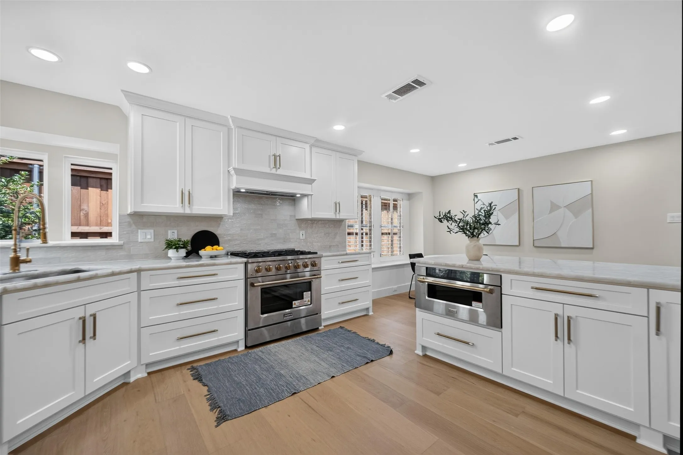 Kitchen featuring white shaker cabinetry, stainless steel appliances, stone countertops, a tile backsplash, and wood-finish flooring
