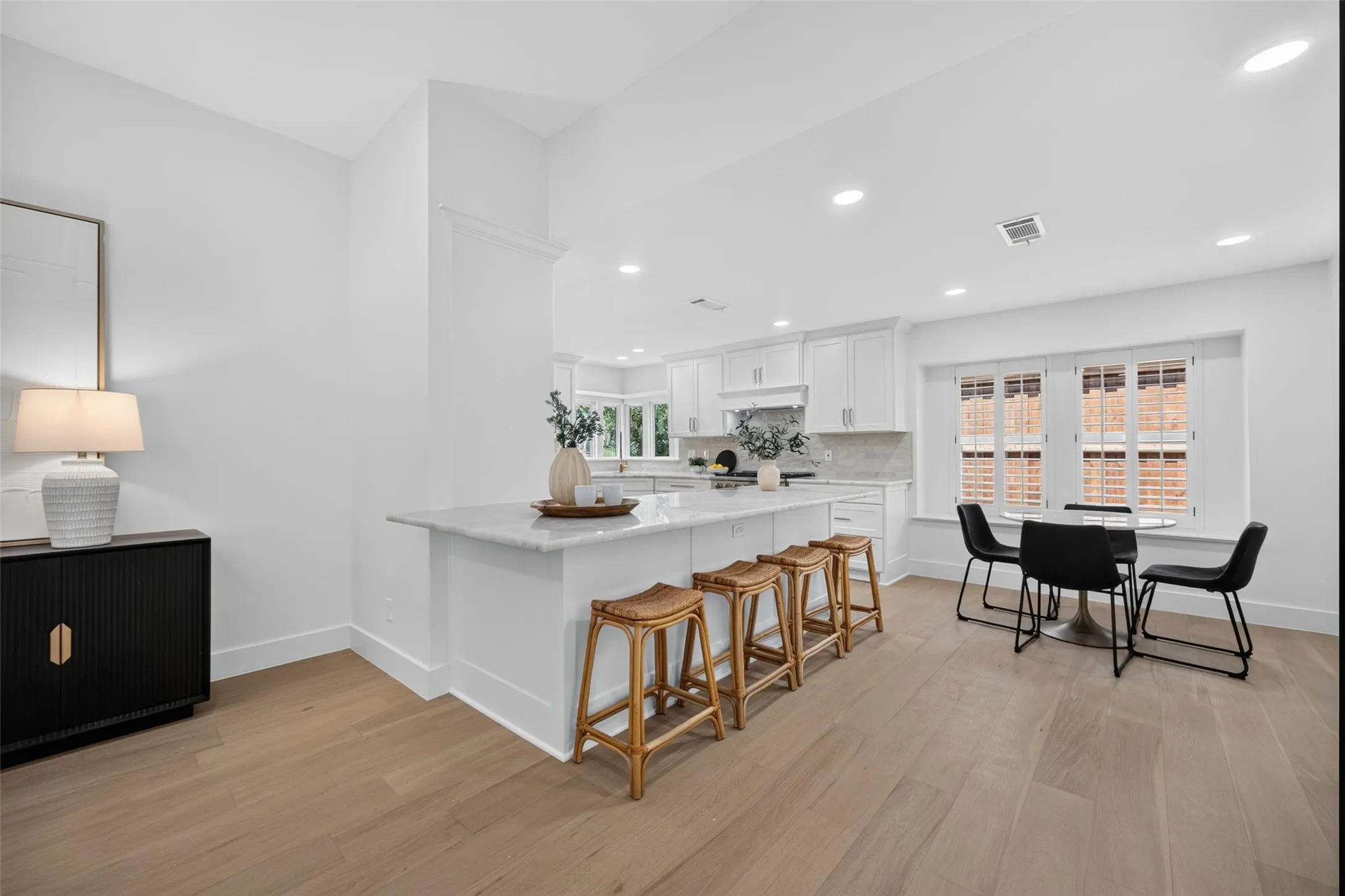 Open-concept kitchen featuring an island with stone countertop, recessed lighting, wood-finish flooring, and white cabinetry