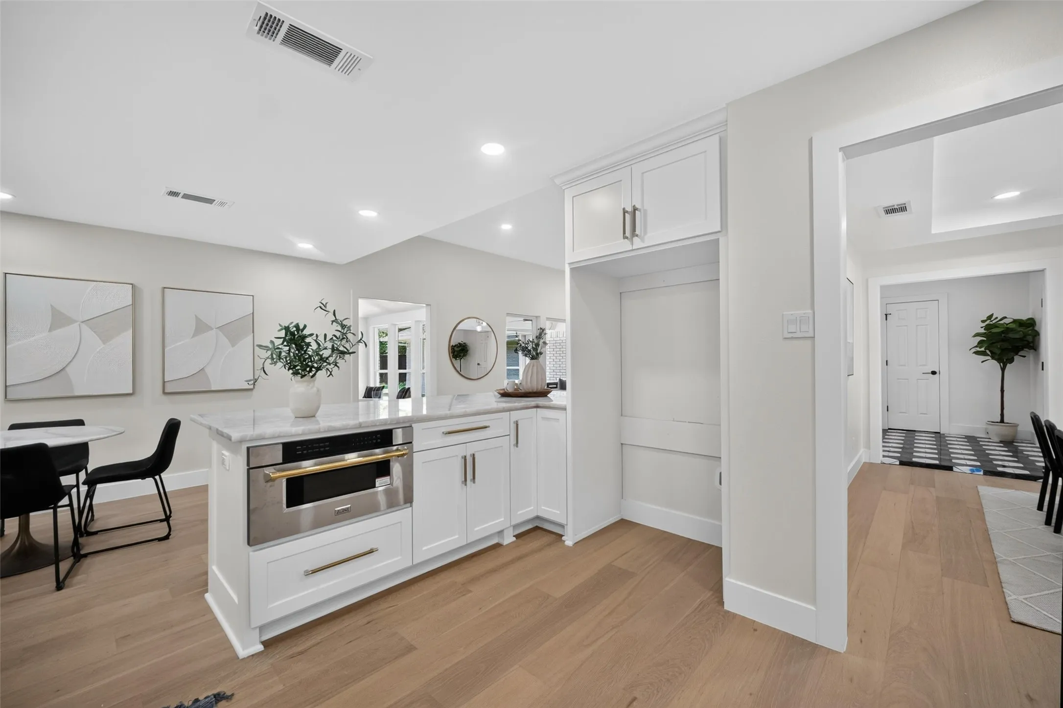 Kitchen island with stone countertop, stainless steel appliance, and white shaker cabinetry