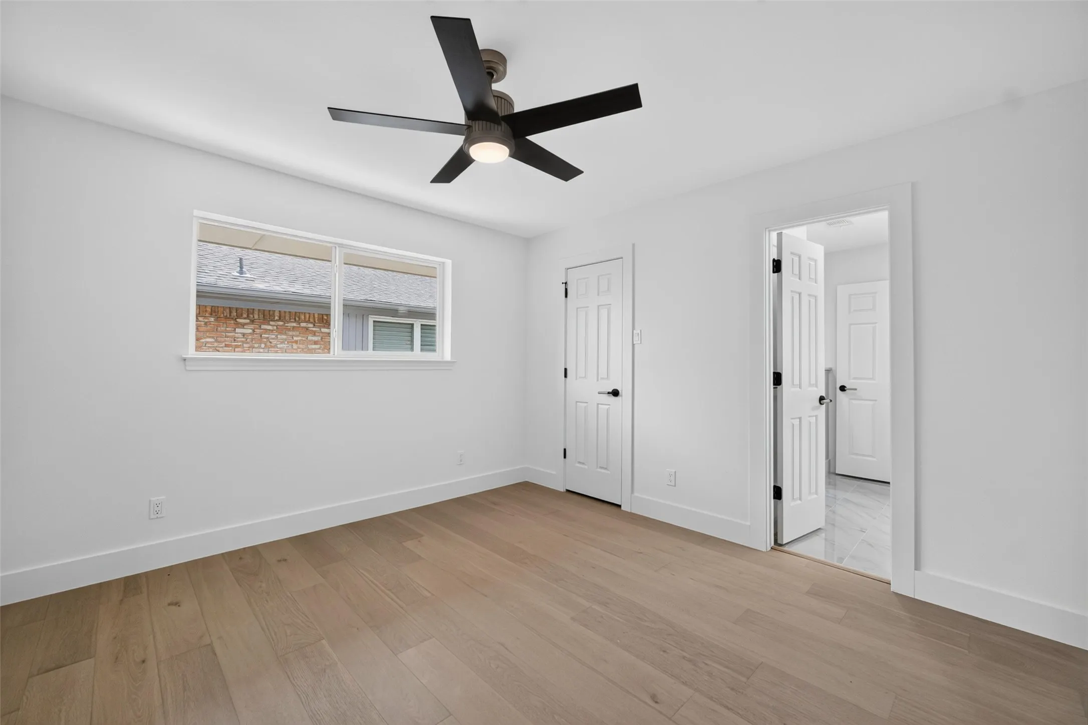 Wood-finish flooring, white walls, and a modern ceiling fan with integrated lighting