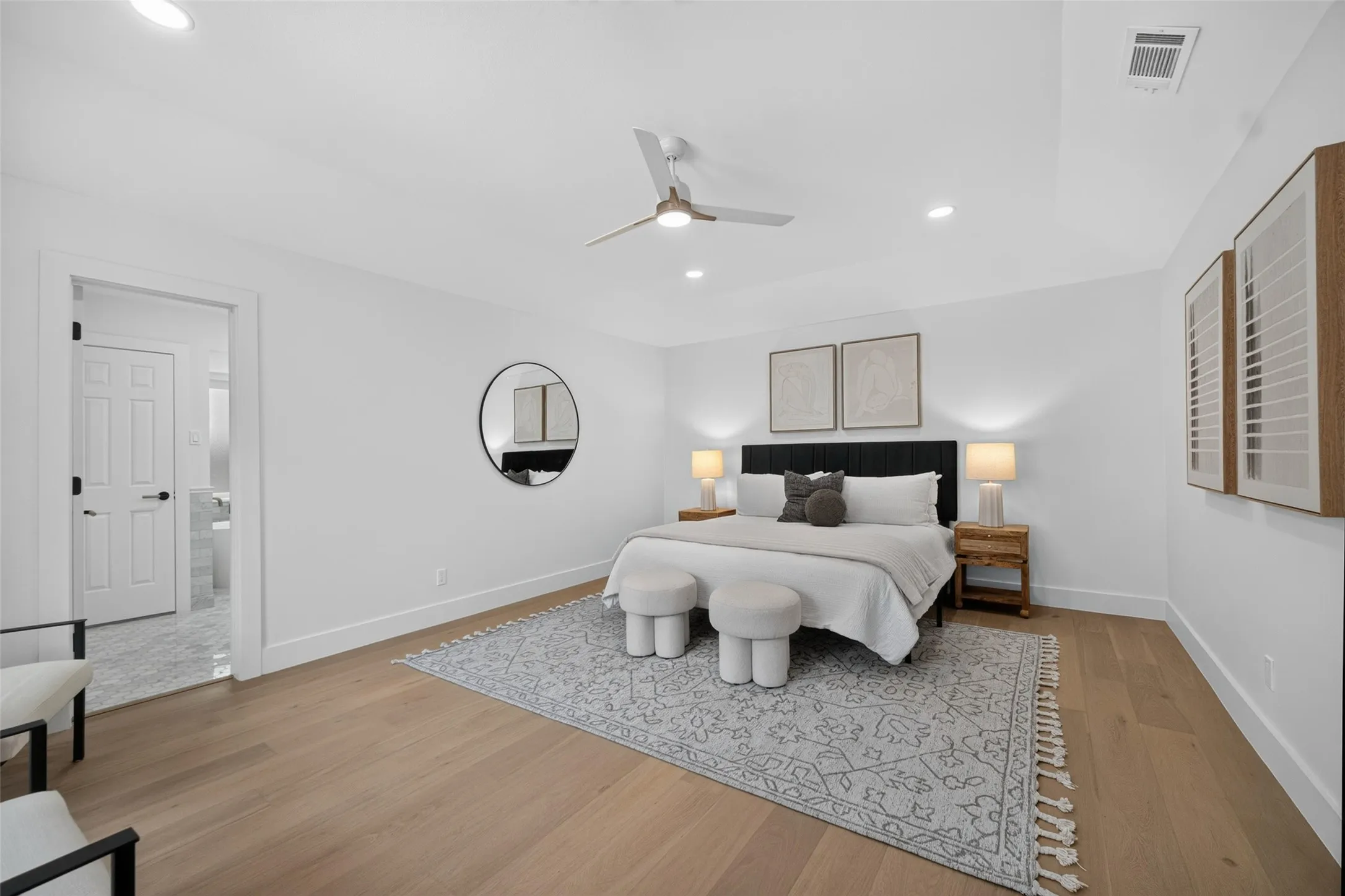Recessed ceiling lighting, wood-finish flooring, ceiling fan, white paneled door, and a tray ceiling