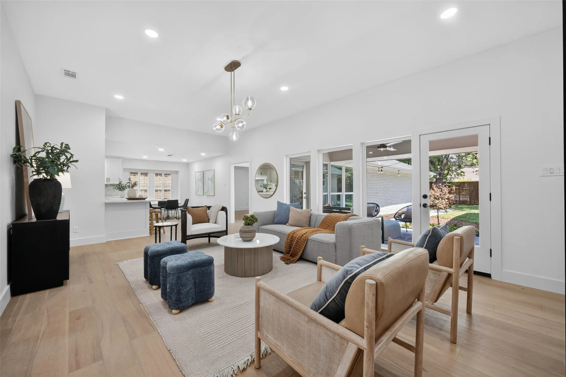 Vaulted ceilings with recessed lighting, wood-finish flooring, a modern chandelier, and a wall of windows with an exterior door