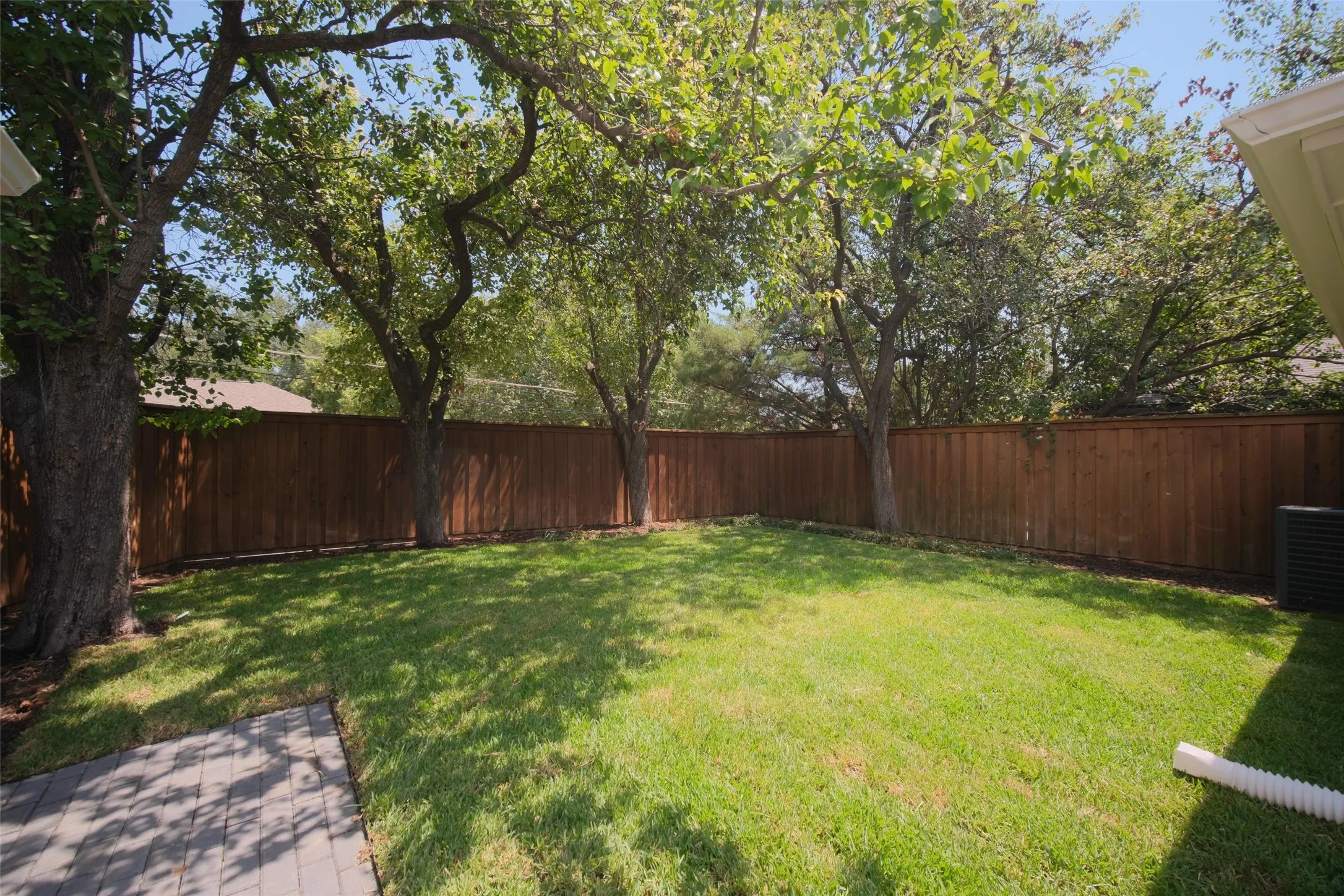 Private backyard featuring mature trees, a wood privacy fence, and a paver patio