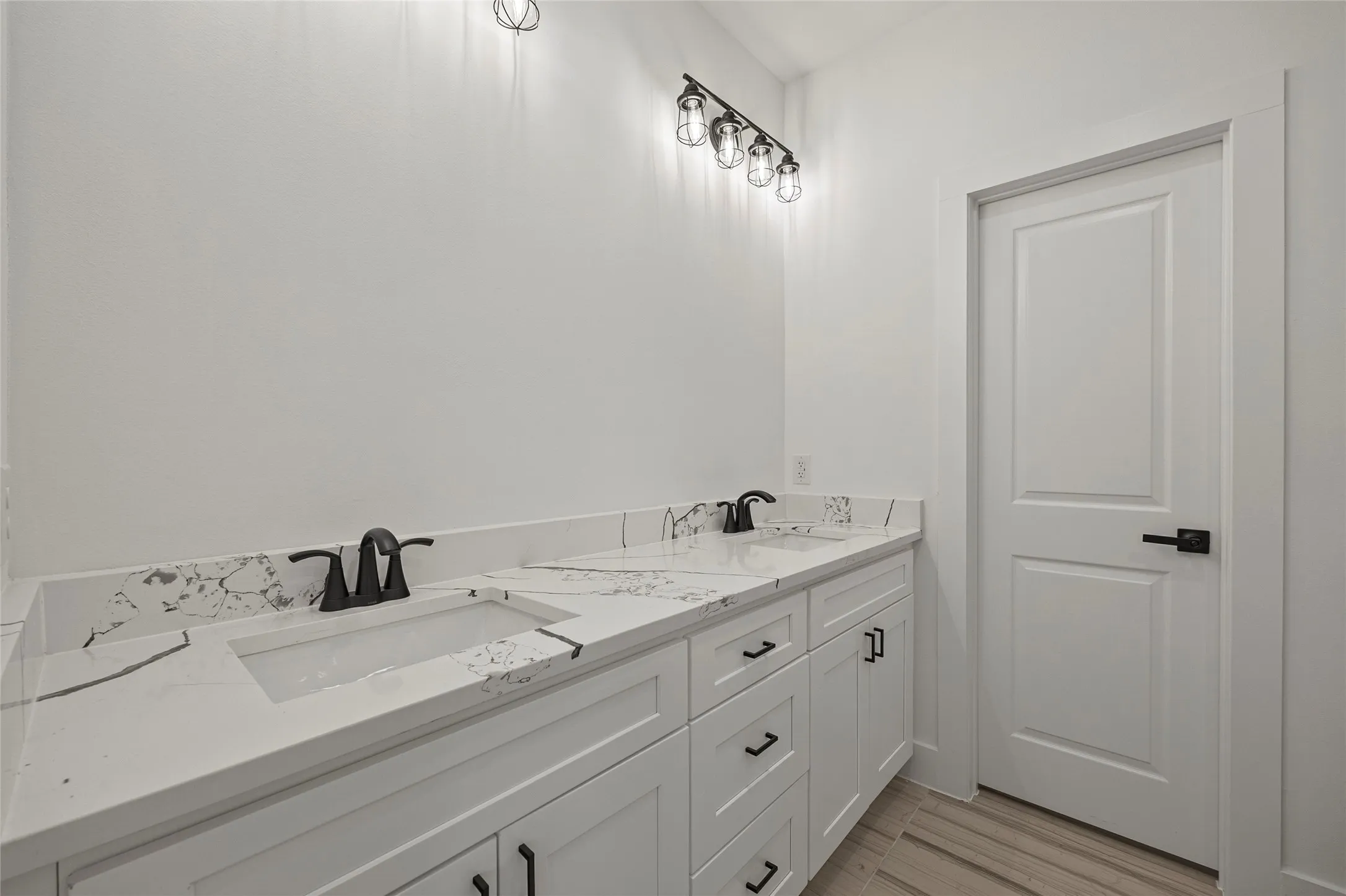 Dual vanity featuring white cabinetry, integrated sinks, black hardware, and patterned countertops