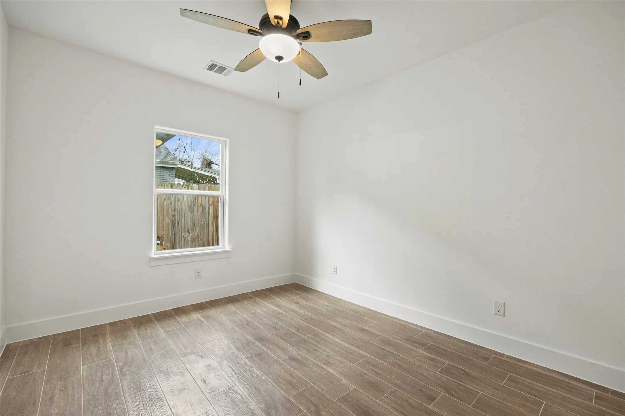 Recessed window, wood-finish tile flooring, ceiling fan with integrated lighting, white walls, and white trim