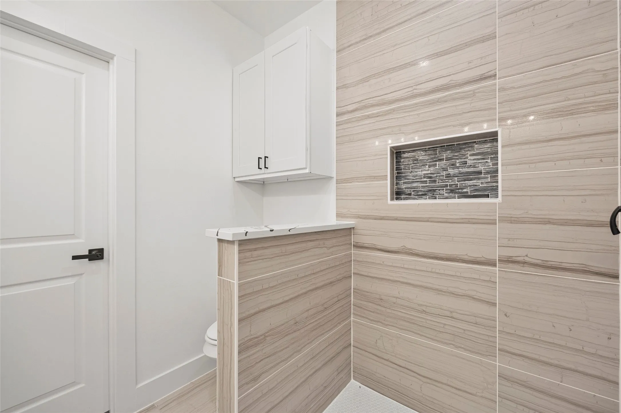 Tiled shower featuring a decorative mosaic niche