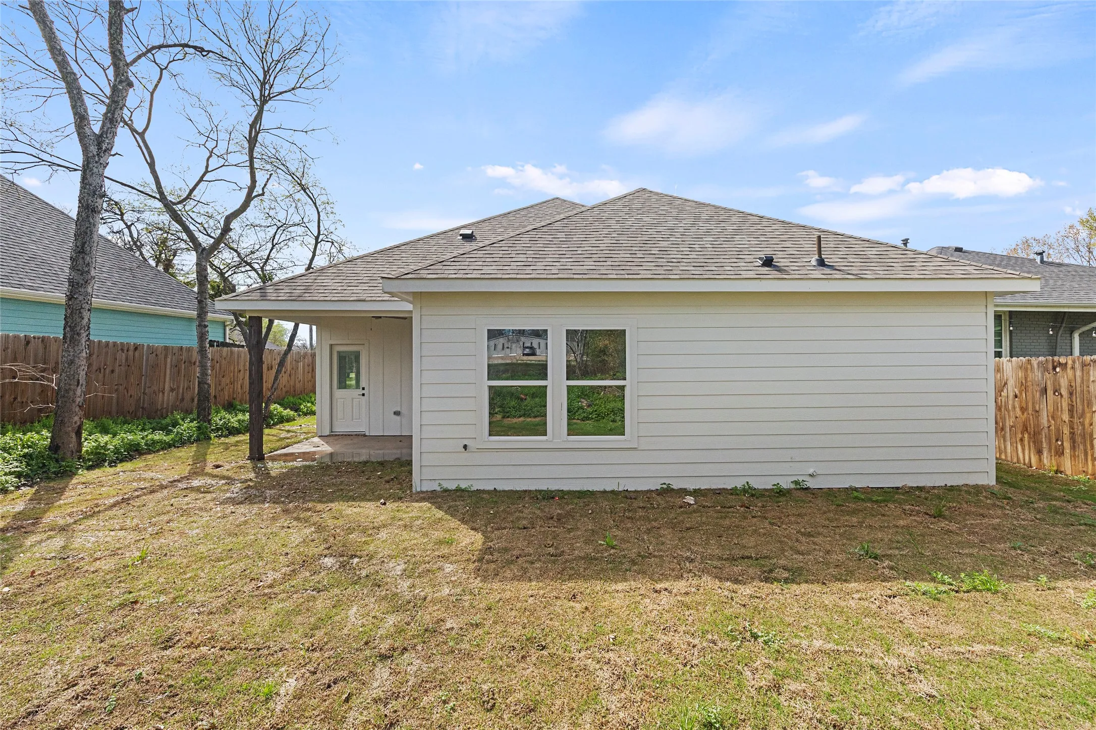 White horizontal siding exterior with a covered concrete patio and a dark shingle roof