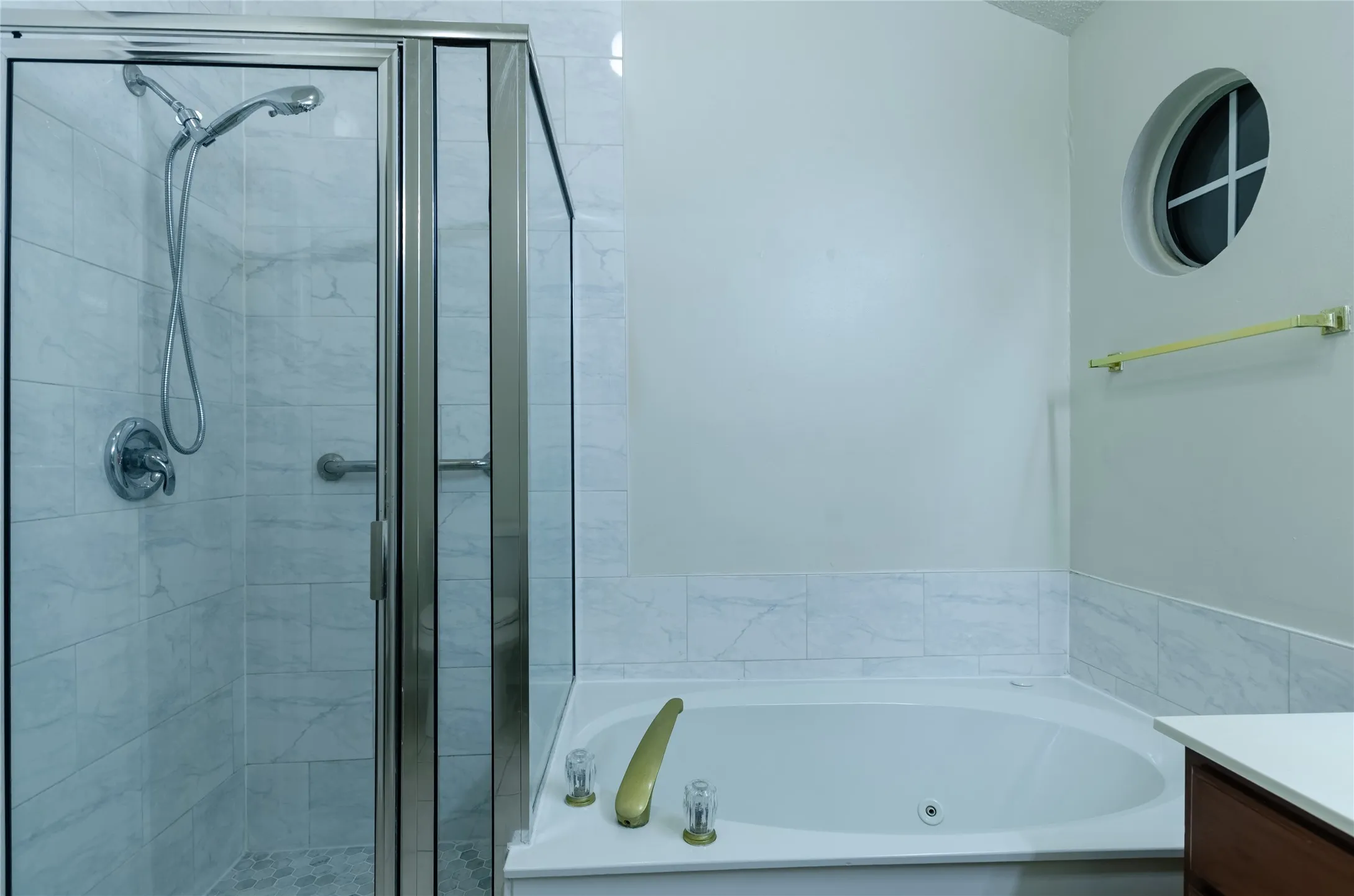 Walk-in shower with clear glass enclosure and handheld shower fixture