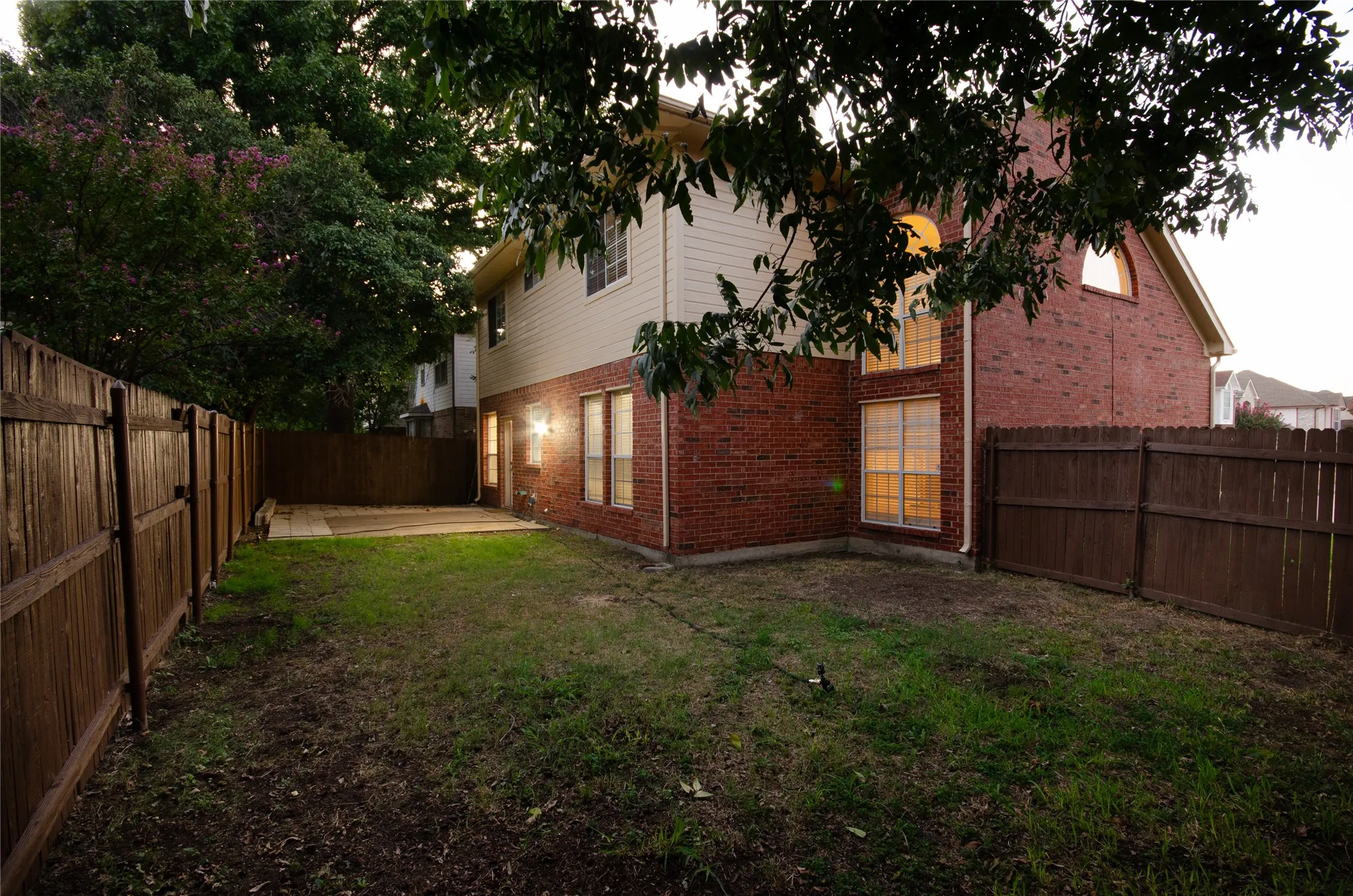 Fenced backyard featuring a concrete patio and a two-story exterior with brick and siding