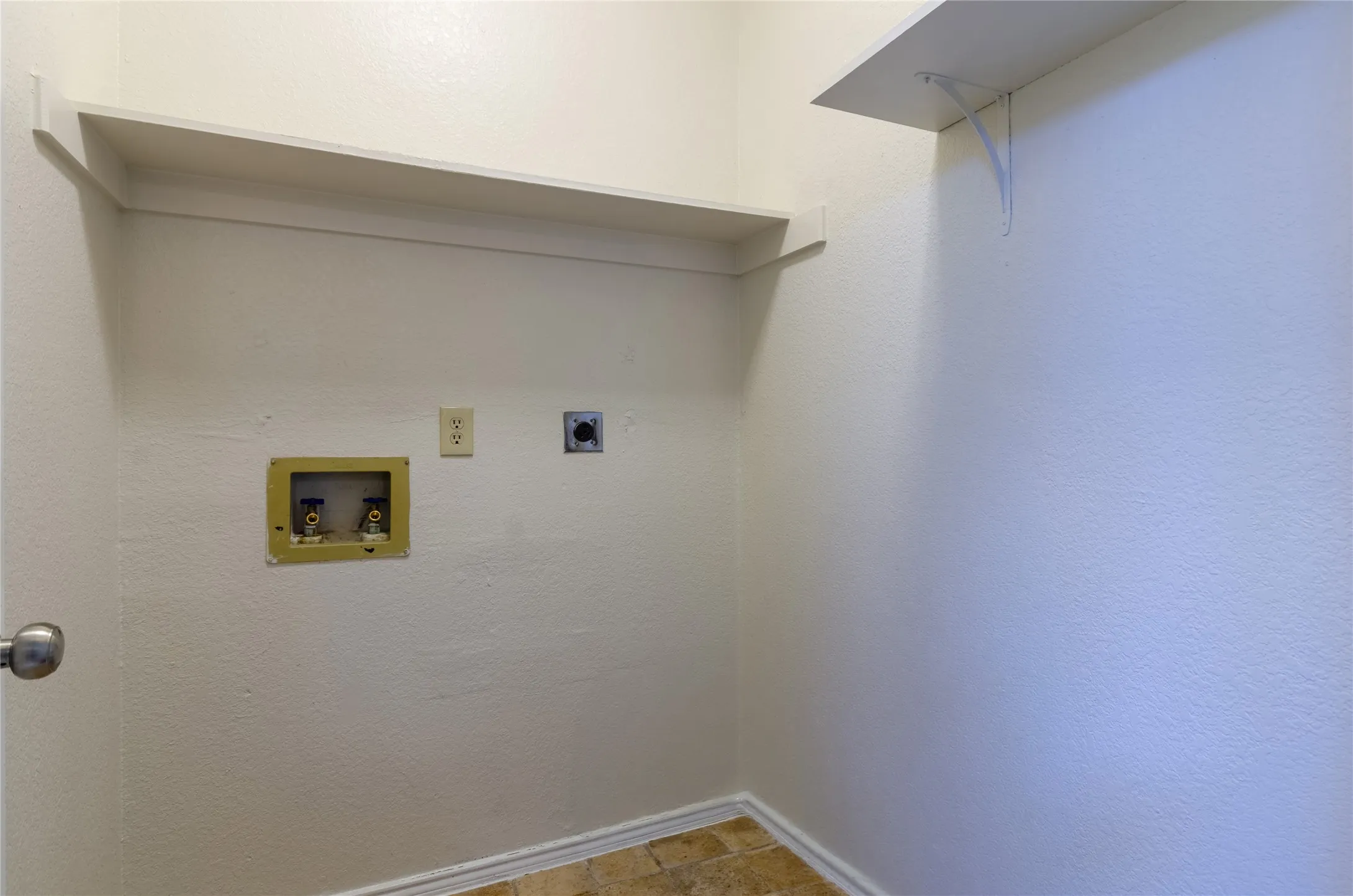 Utility area featuring upper shelving and wall connections for appliances