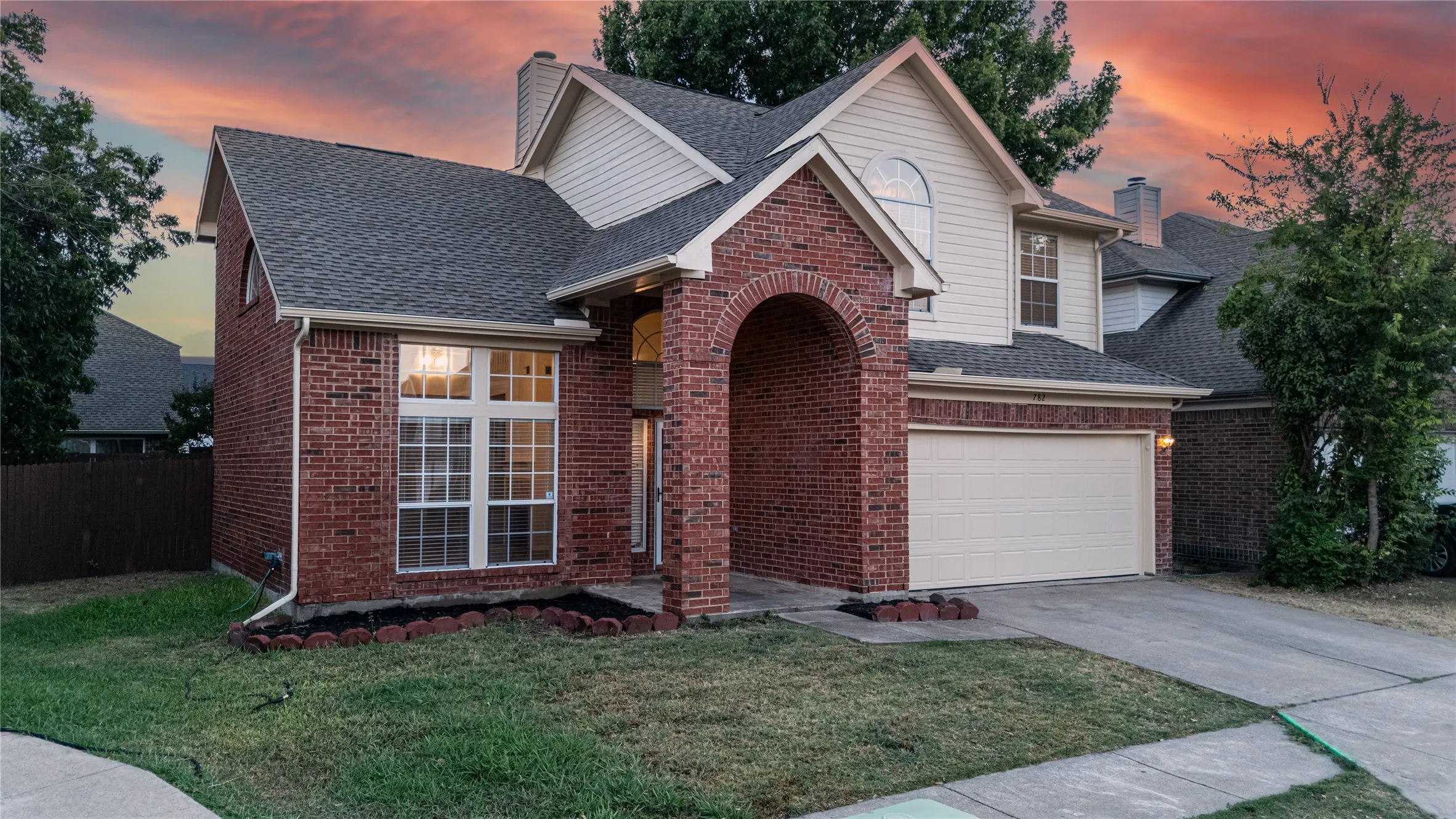 Red brick and siding exterior with an arched entry and attached garage
