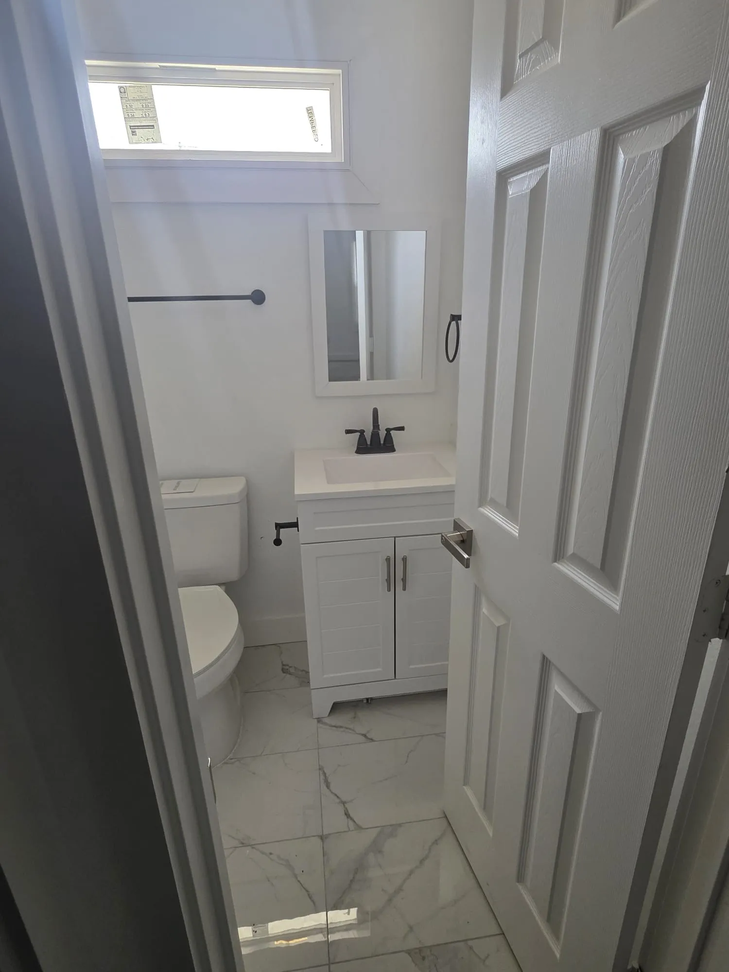 Contemporary bathroom featuring a single vanity with integrated sink, panel cabinetry, matte black fixtures, and tile flooring