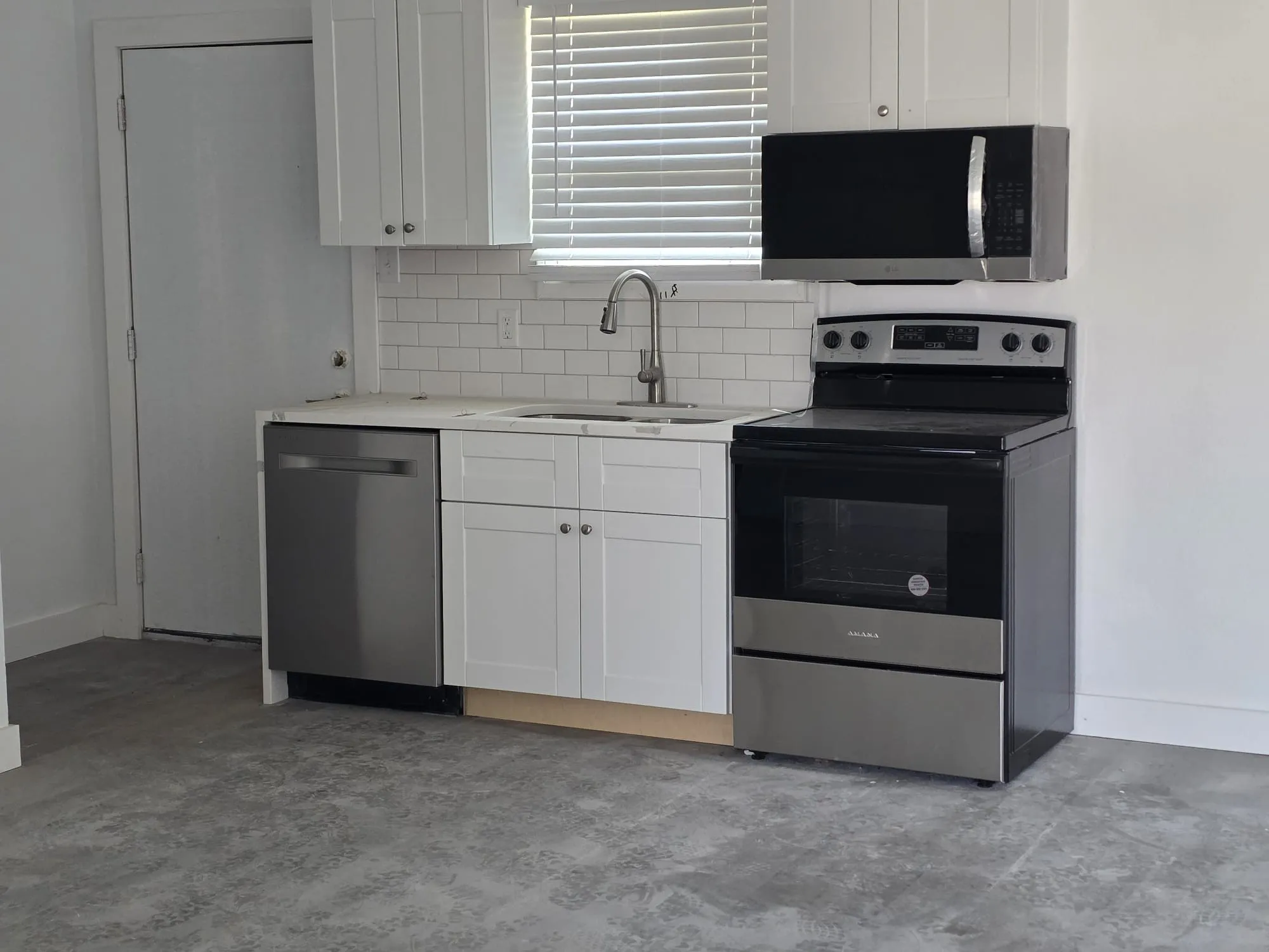 Kitchen featuring white shaker cabinetry, stainless steel appliances, a subway tile backsplash, and a stainless steel sink with a gooseneck faucet