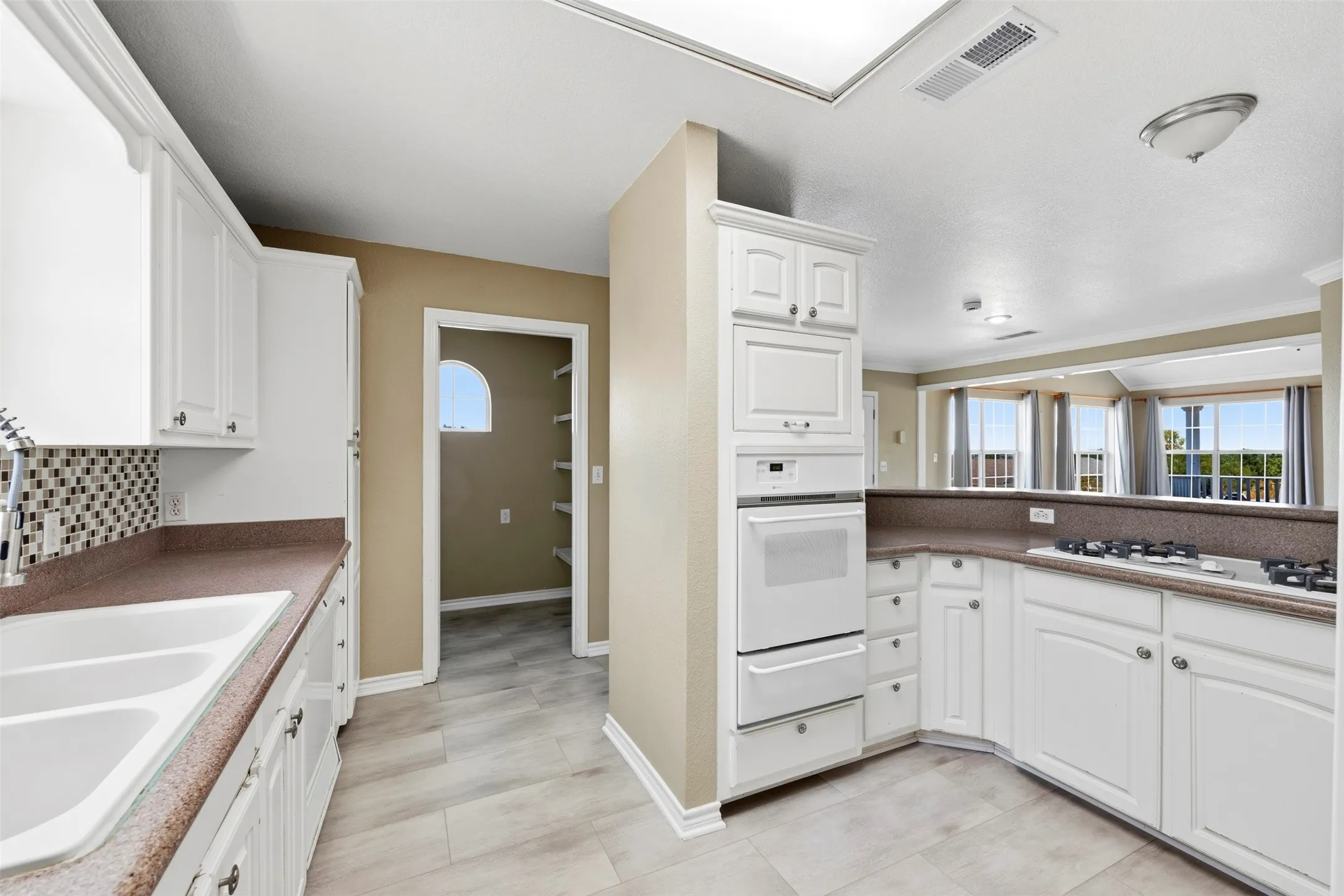Kitchen with white cabinetry, built-in double ovens, a gas cooktop, and a tile backsplash