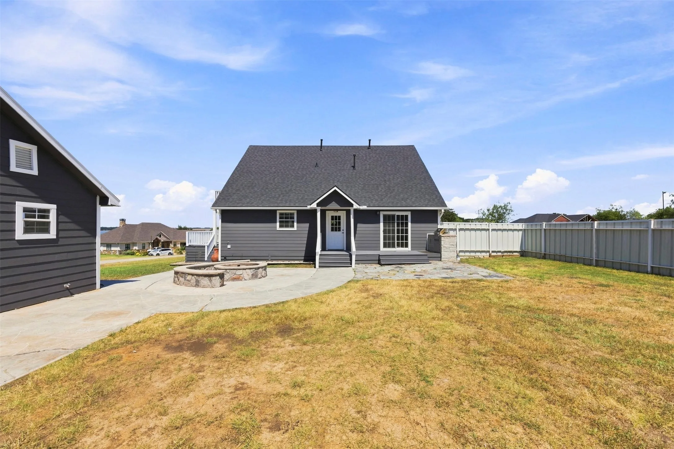 Rear exterior with horizontal siding, a stone-clad fire pit, and a concrete patio