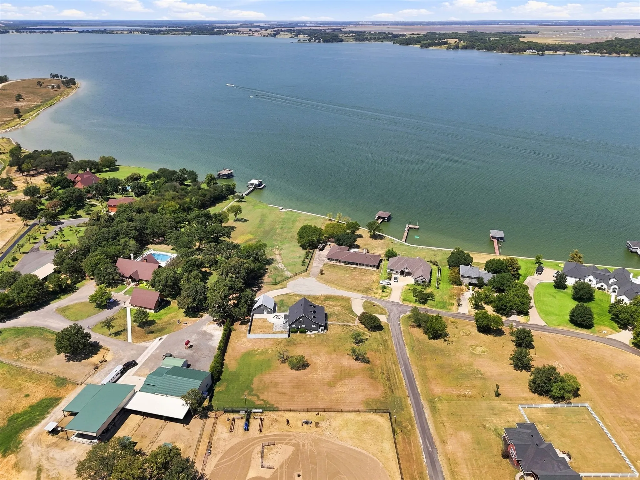 Waterview property offering expansive grounds with mature landscaping, multiple residential structures, direct water access with dock facilities, and scenic lakeside positioning overlooking open water and distant shoreline