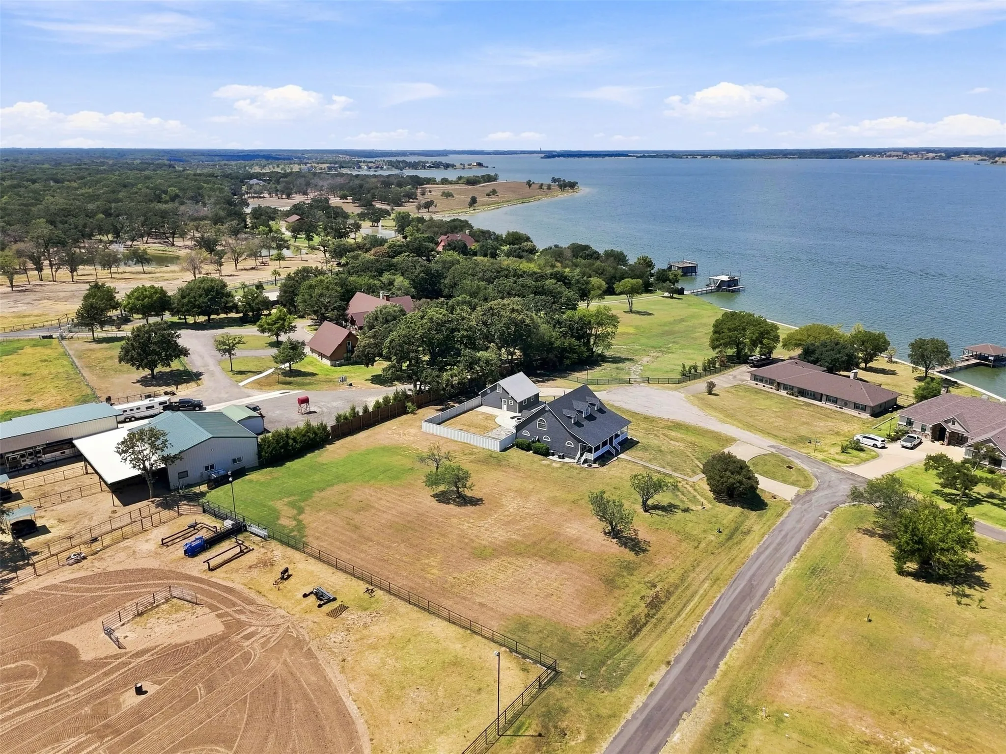 Waterviewt property featuring a main residence with a gabled roof, an equestrian training arena, multiple outbuildings, and a private dock