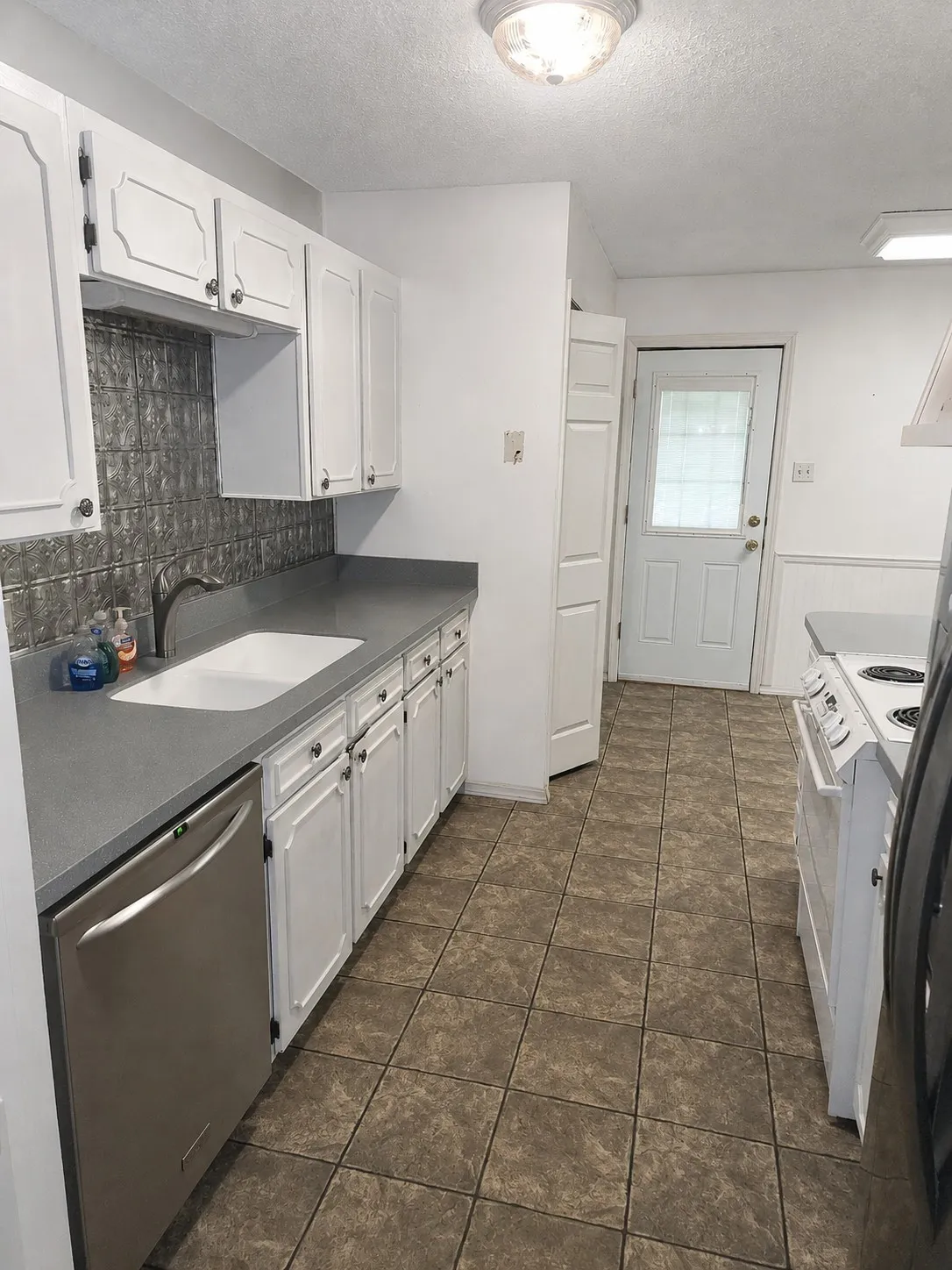 White cabinetry with dark hardware, a tiled backsplash, and stone-finish countertops