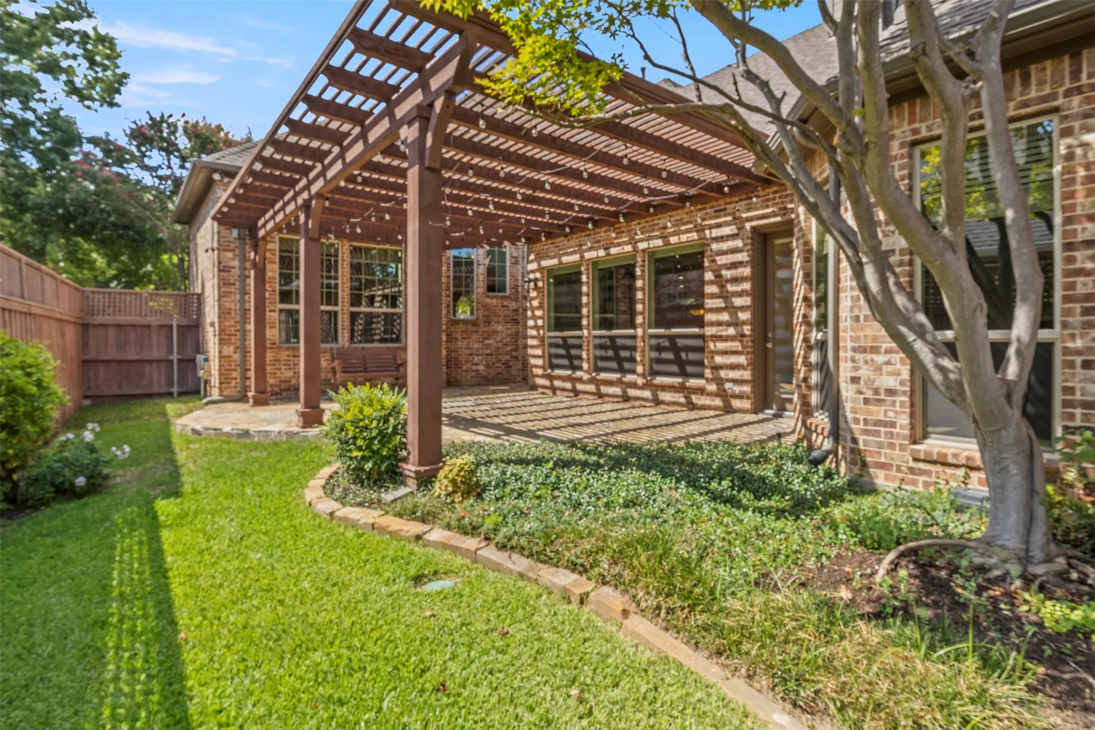 Easy care yard with stone patio and pergola.