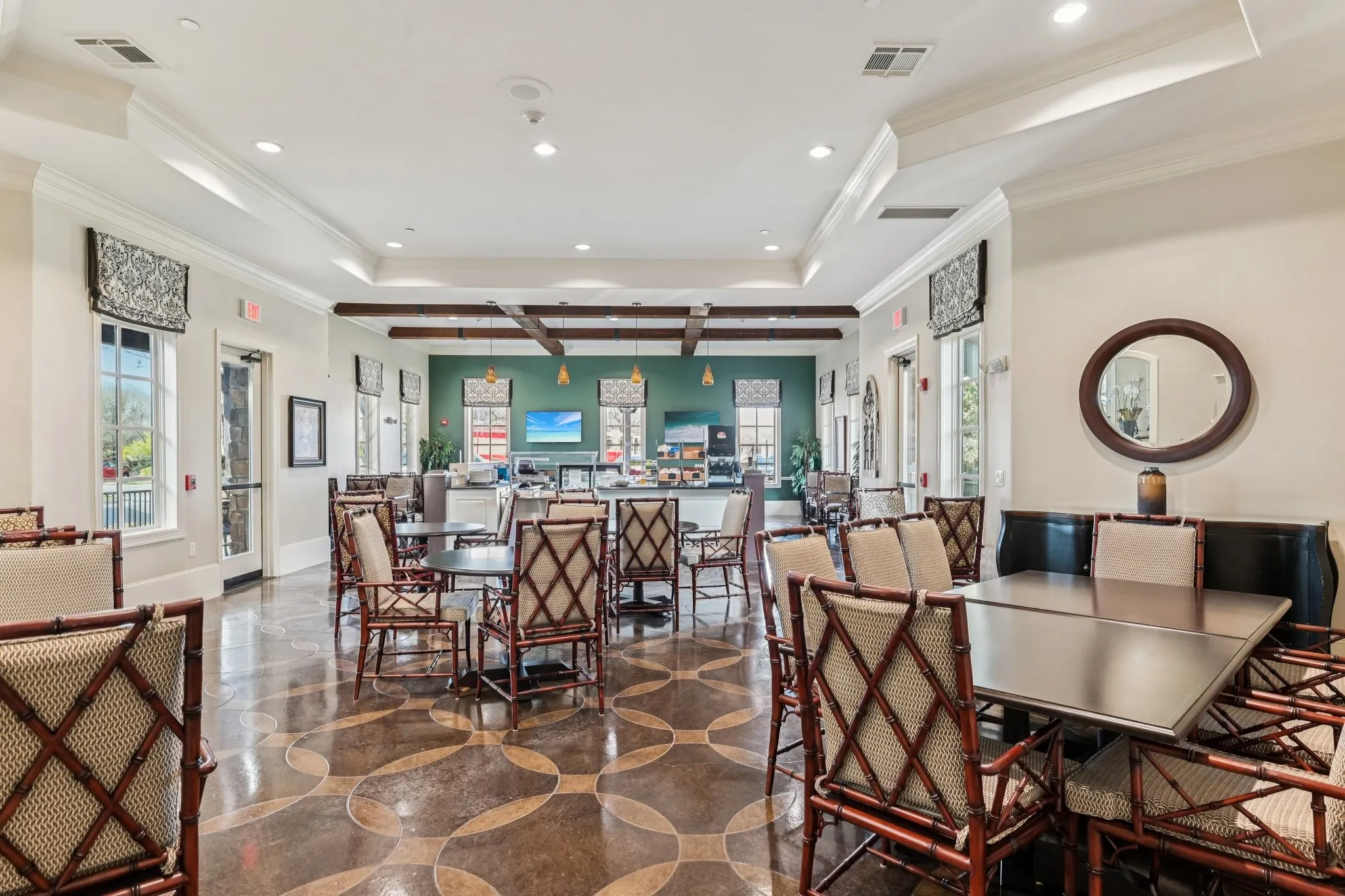 Spacious common area featuring patterned flooring, tray ceilings with recessed lighting, and exposed ceiling beams