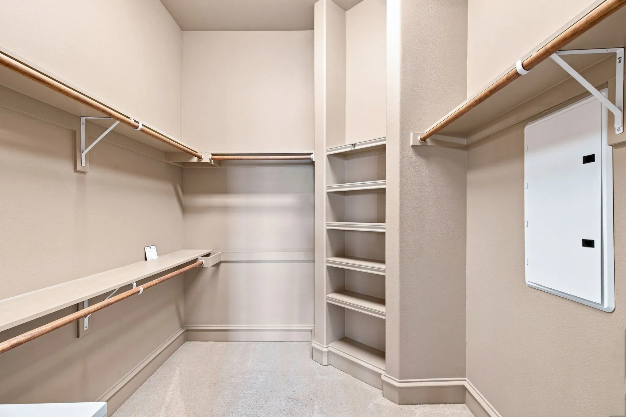 Walk-in closet with built-in shelving, multiple hanging rods, and an integrated corner shelving unit