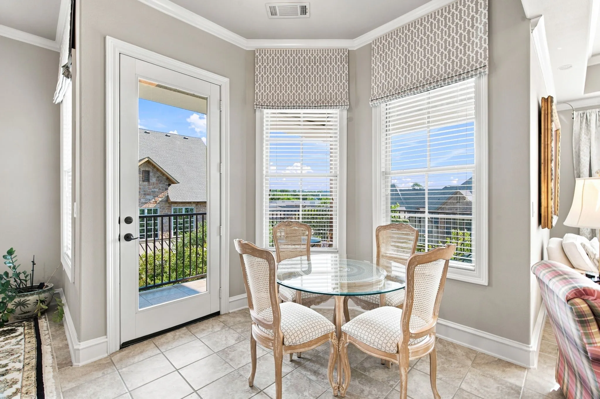 Bay window with three window panes, a glass-paneled door, and tiled flooring
