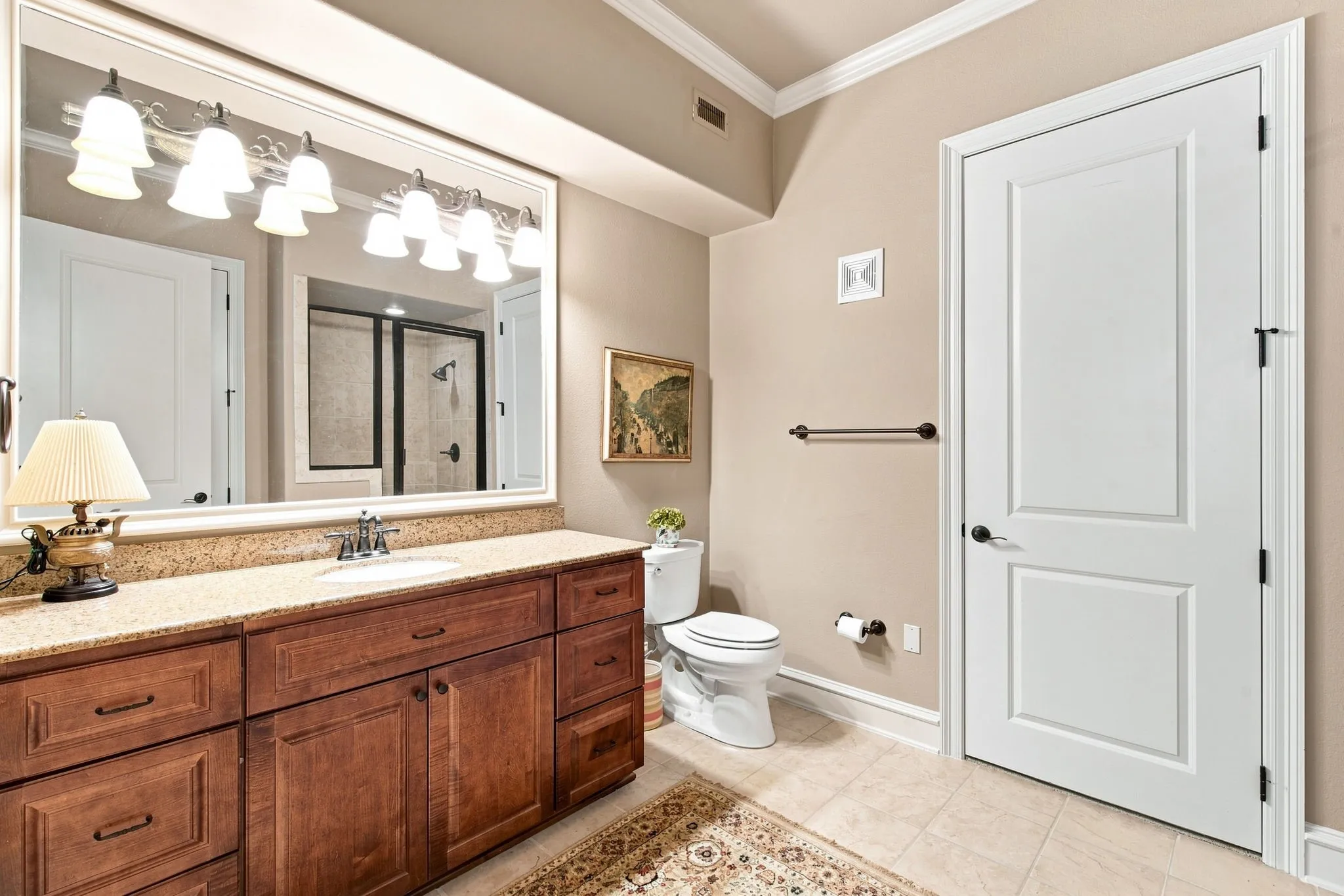 Wood-finish vanity with a light-toned countertop, undermount sink, and polished chrome faucet