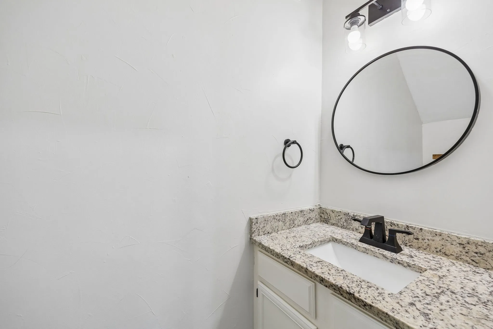 Bathroom vanity featuring a speckled countertop, integrated sink, and matte black faucet