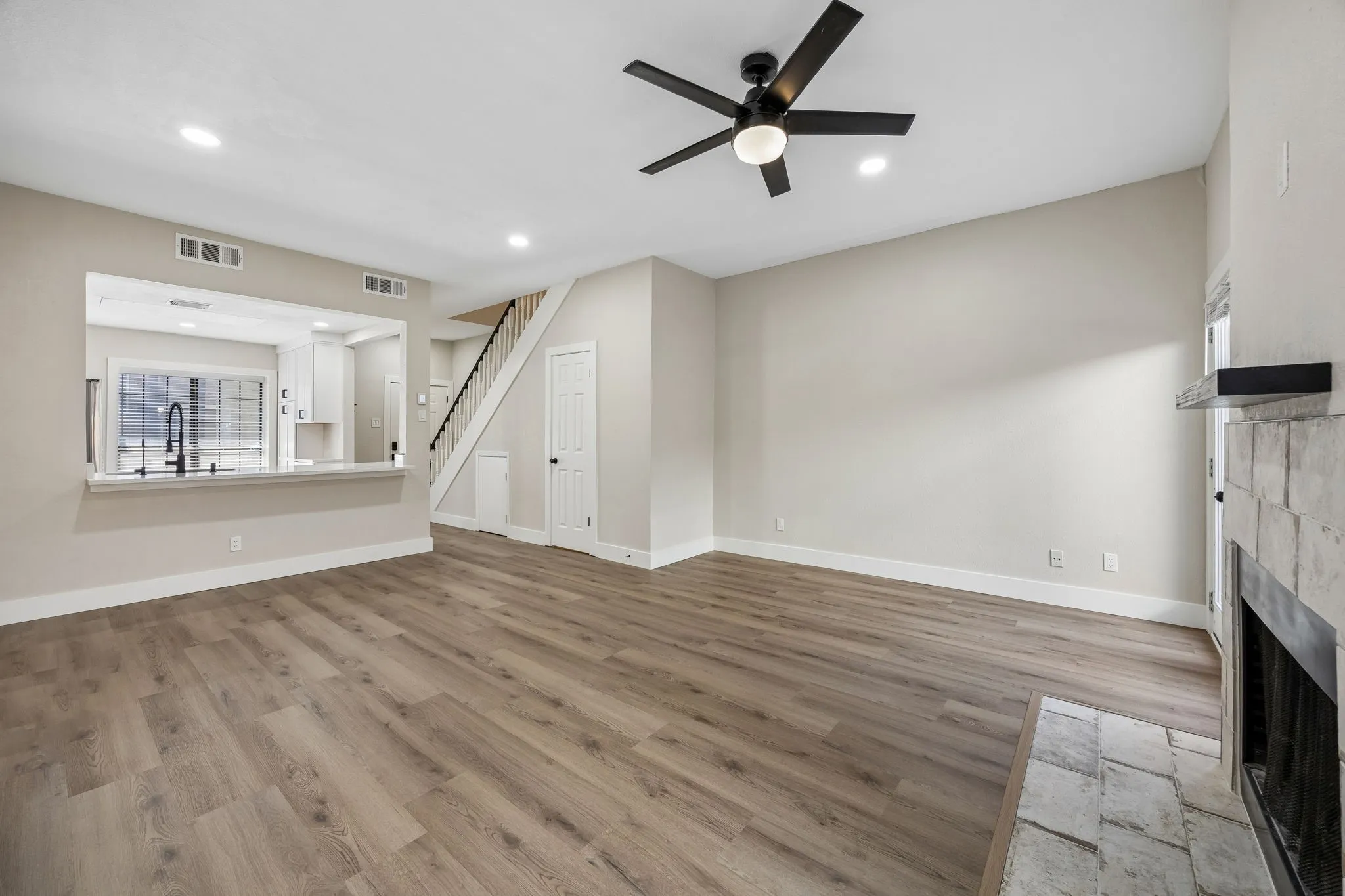 Spacious living area featuring wood-finish flooring, a contemporary ceiling fan, and recessed lighting