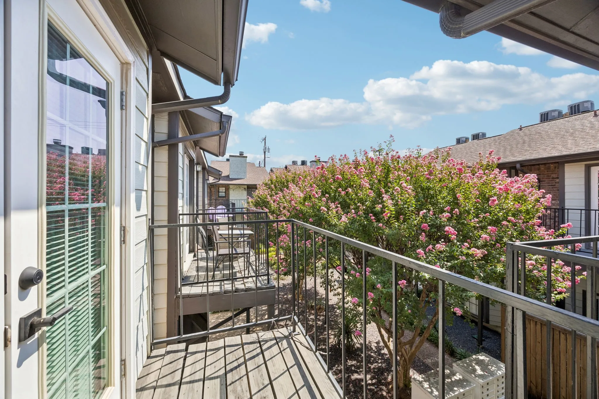 Wood-deck balcony featuring dark metal railings and a glass-paneled door