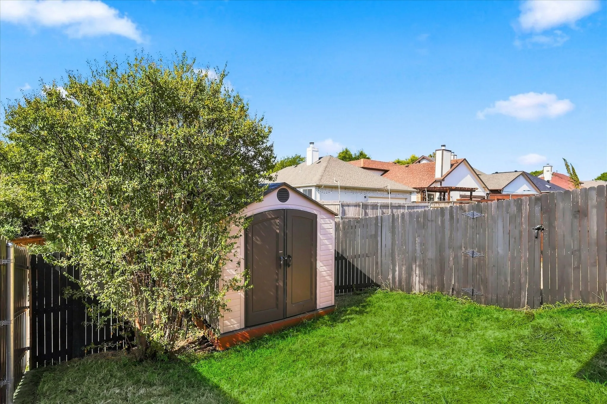 Expansive backyard featuring a manicured lawn, a detached storage shed, a privacy fence, and mature landscaping