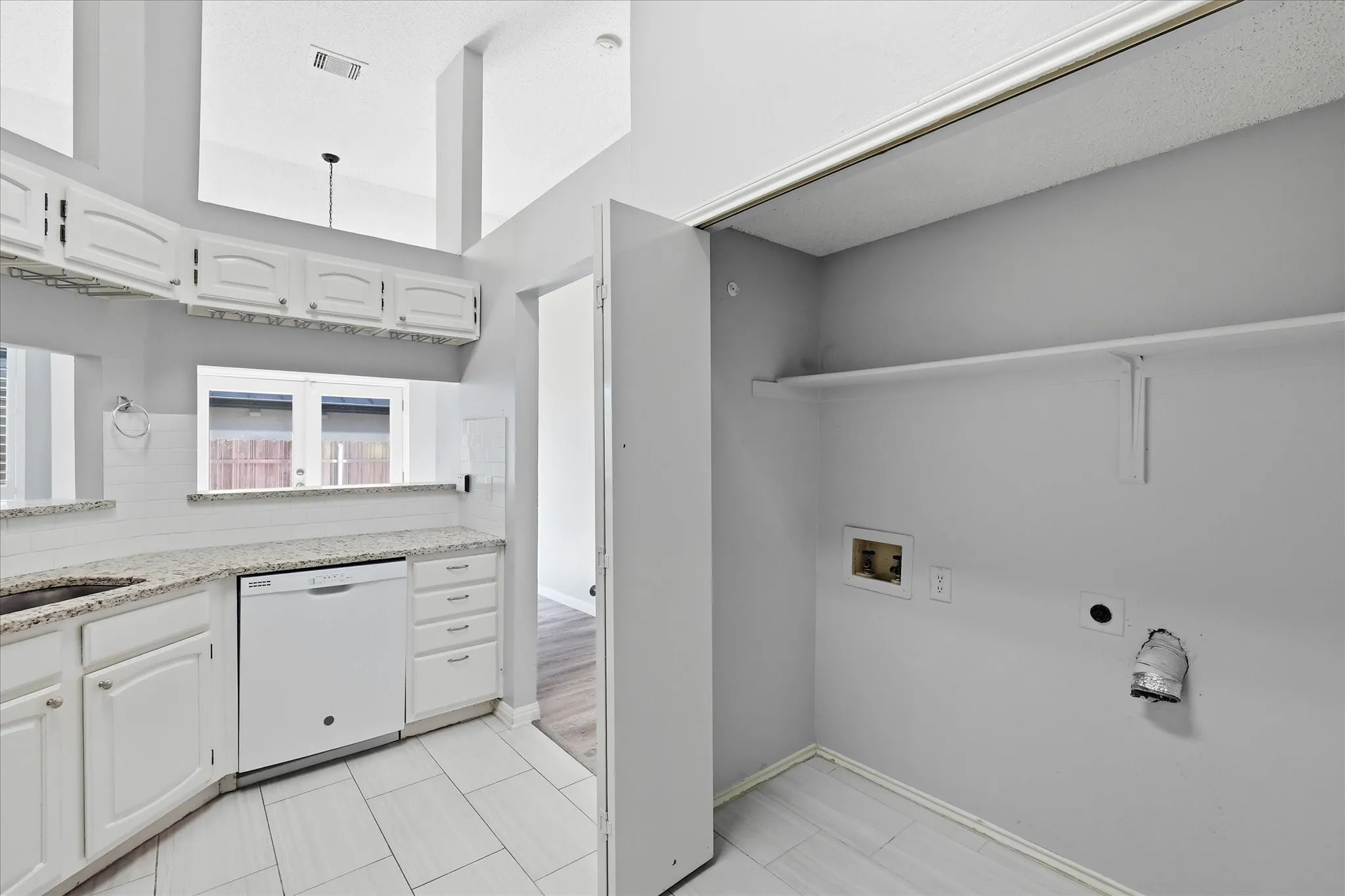 Kitchen featuring white cabinetry, light-toned countertops, a built-in dishwasher, and a white subway tile backsplash