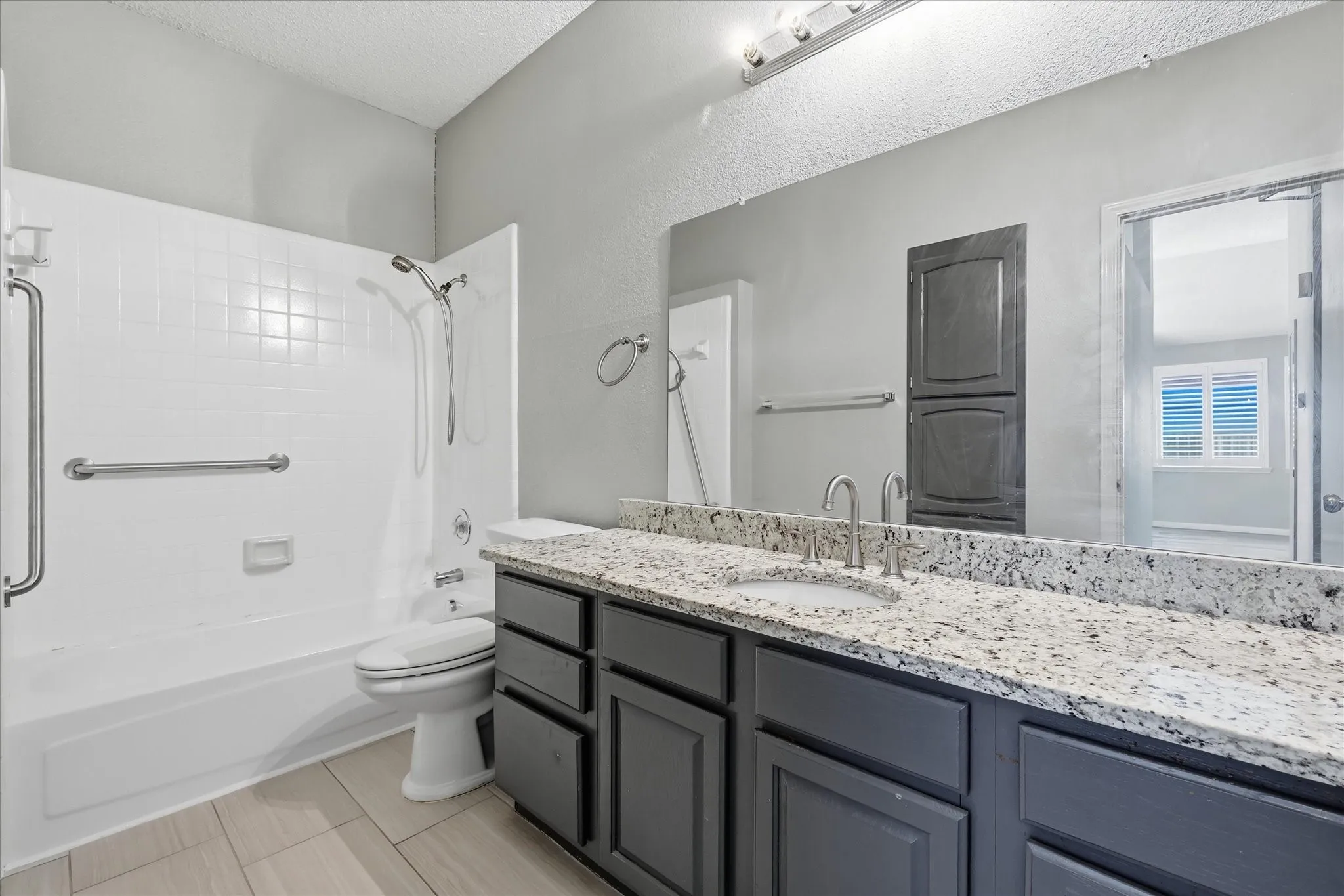 White tiled shower and bathtub combination with grab bars