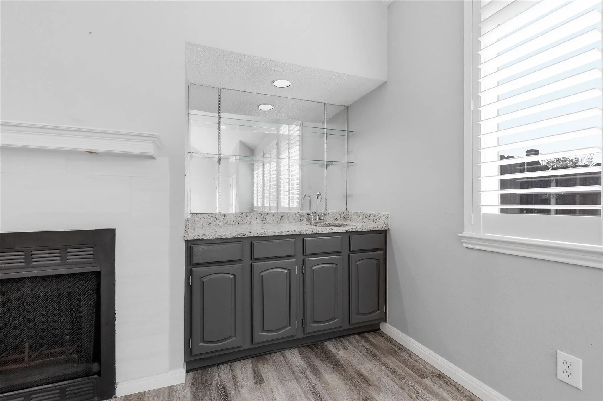 Built-in wet bar with a single basin sink, gray cabinetry, and a light-toned countertop
