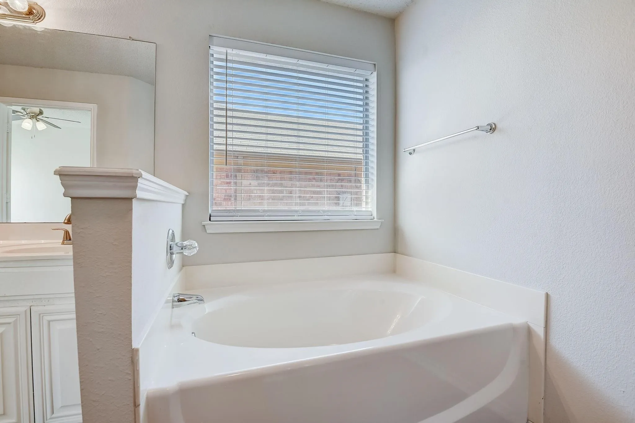 Bathroom featuring a garden tub, vanity, and a ceiling fan