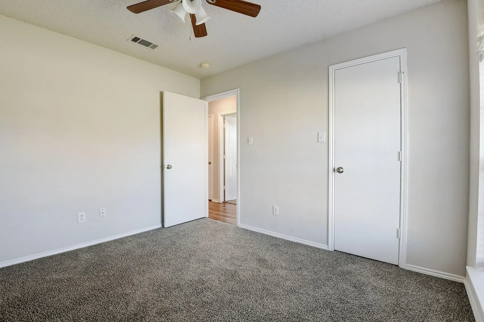 Unfurnished bedroom with visible vents, baseboards, ceiling fan, carpet, and a textured ceiling