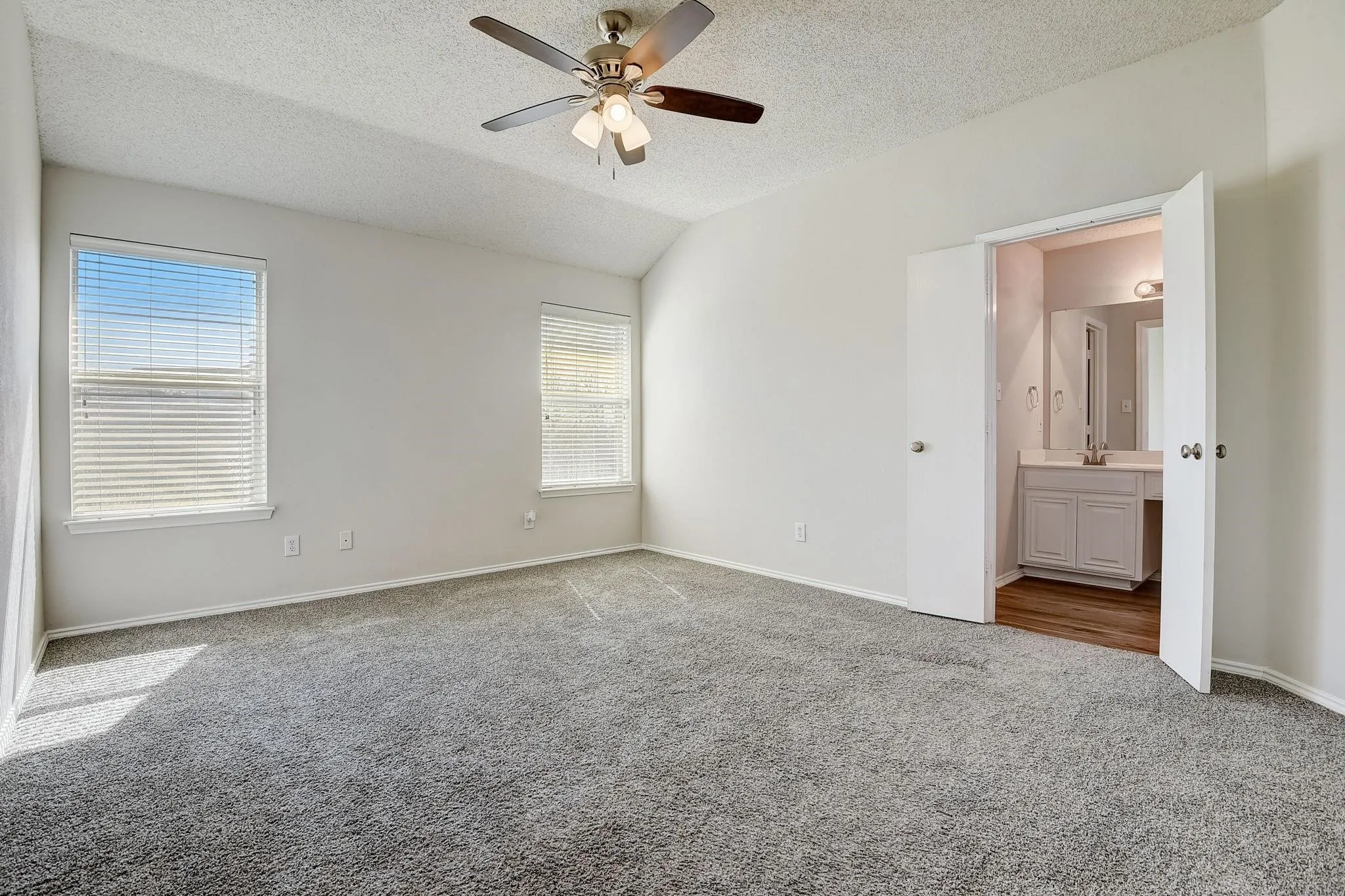 Unfurnished bedroom featuring a textured ceiling, carpet floors, vaulted ceiling, and baseboards