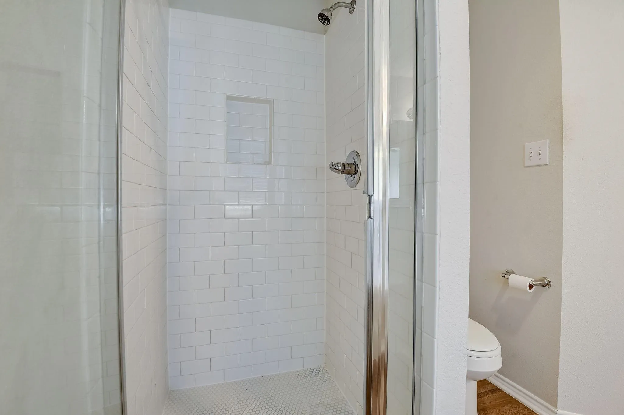 Full bathroom with a stall shower, baseboards, toilet, and wood finished floors