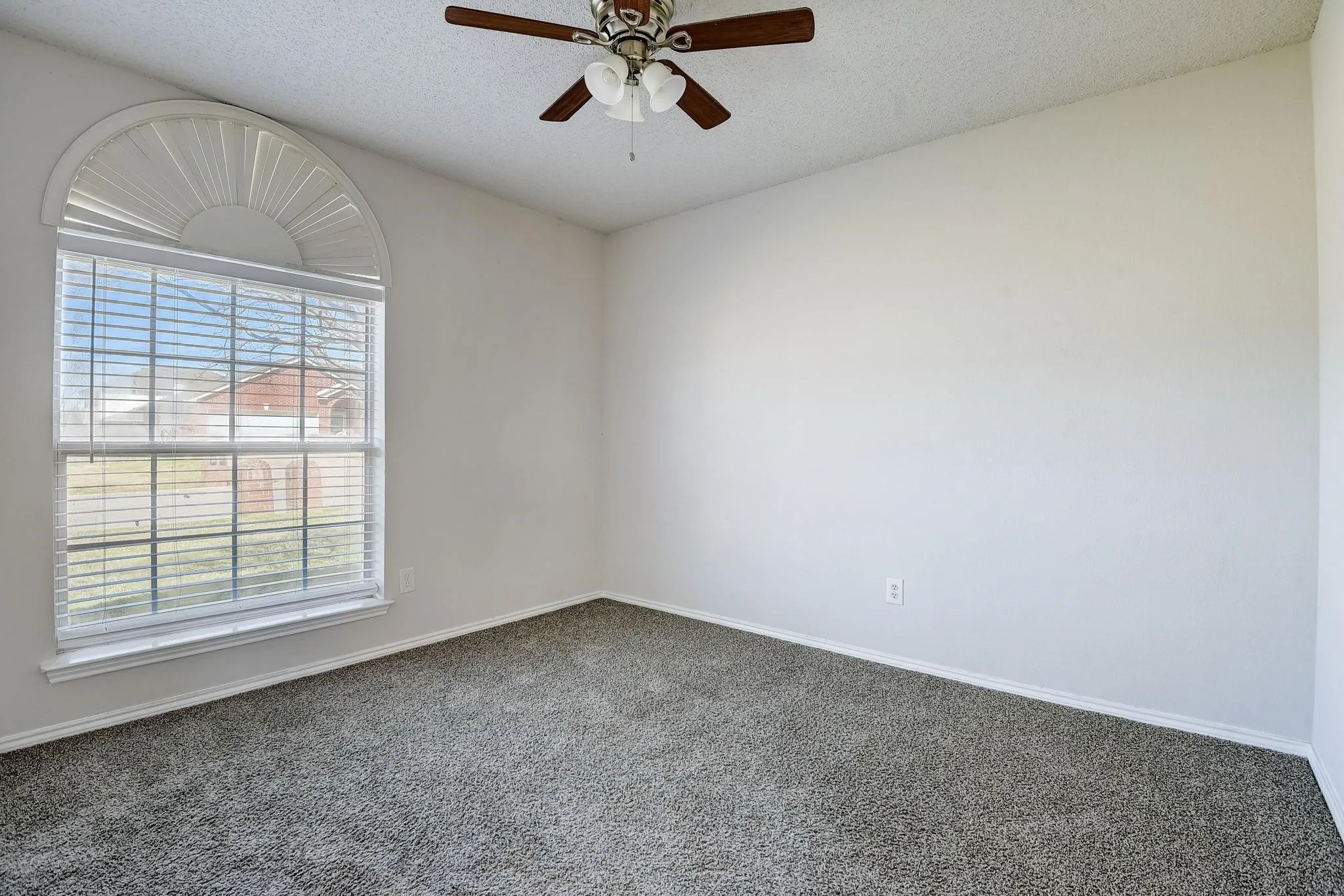 Unfurnished room with a textured ceiling, dark colored carpet, plenty of natural light, and a ceiling fan