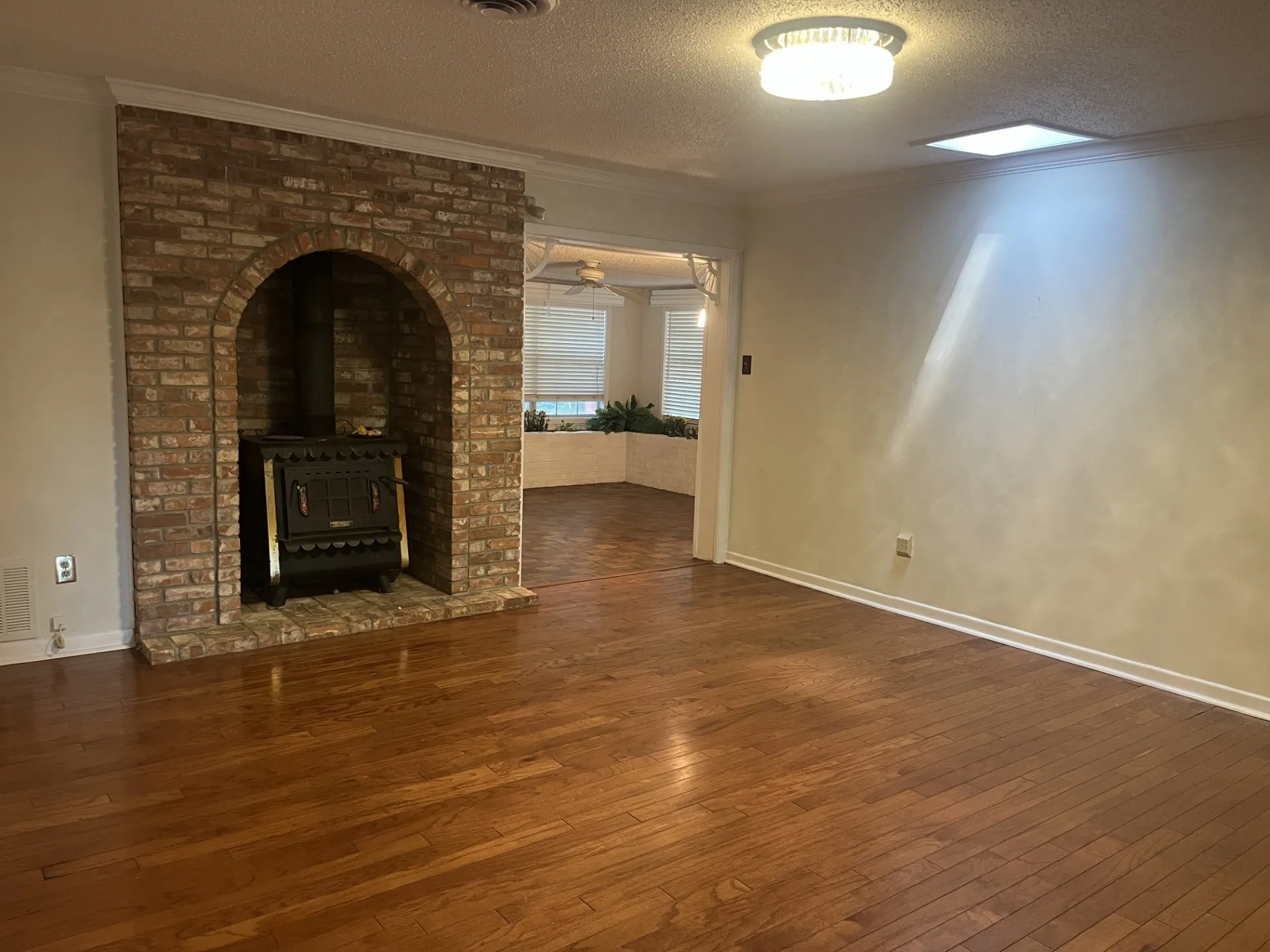 Wood-finish flooring throughout, featuring a brick fireplace with a wood-burning stove