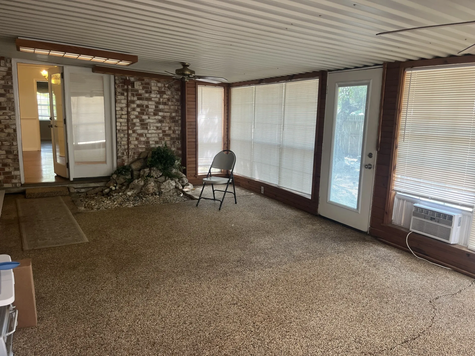 Expansive sunroom featuring an exposed brick wall, multiple window panels, and a full-light exterior door
