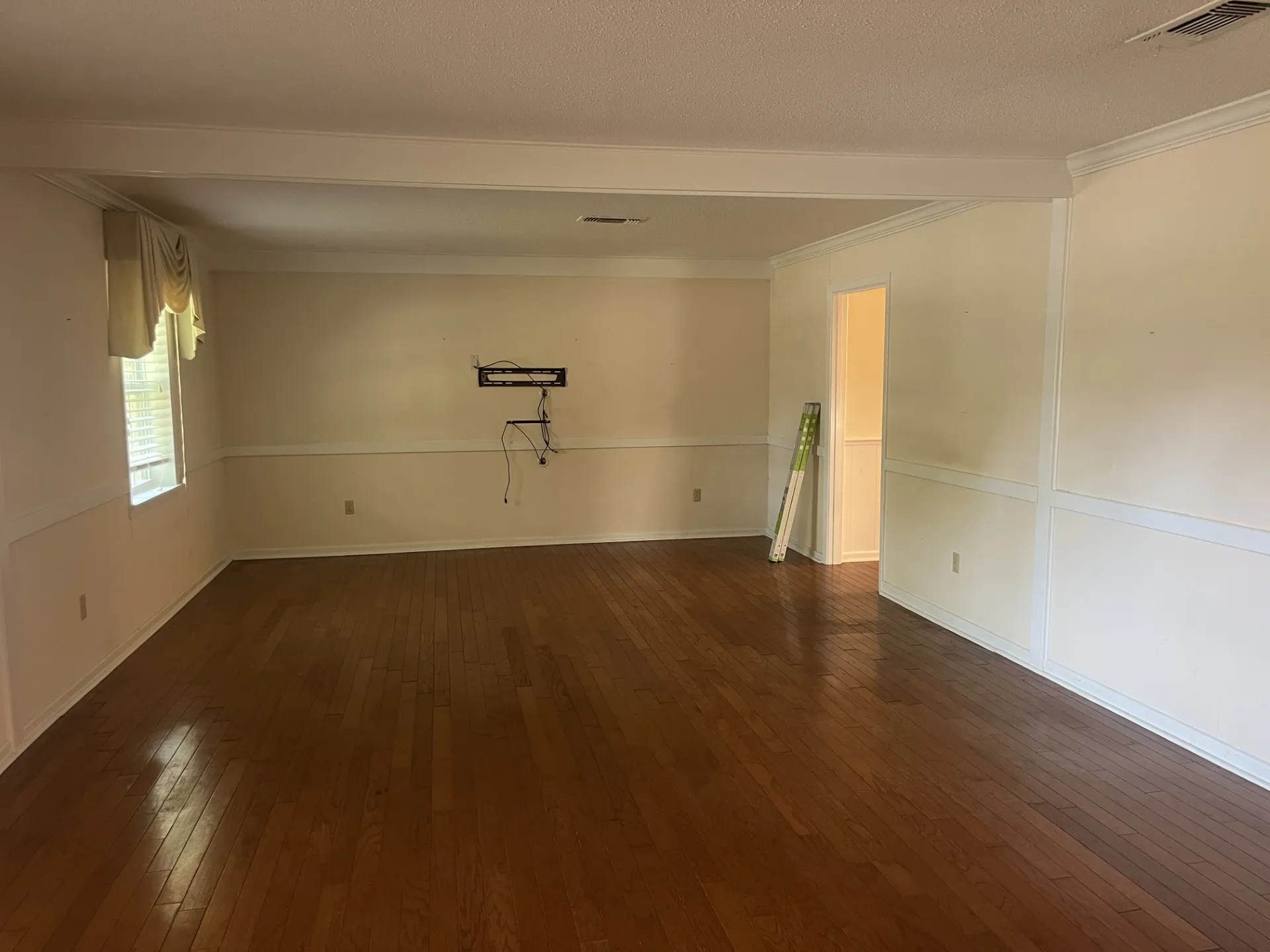 Wood-finish flooring throughout, bright walls, decorative wall paneling, and crown molding